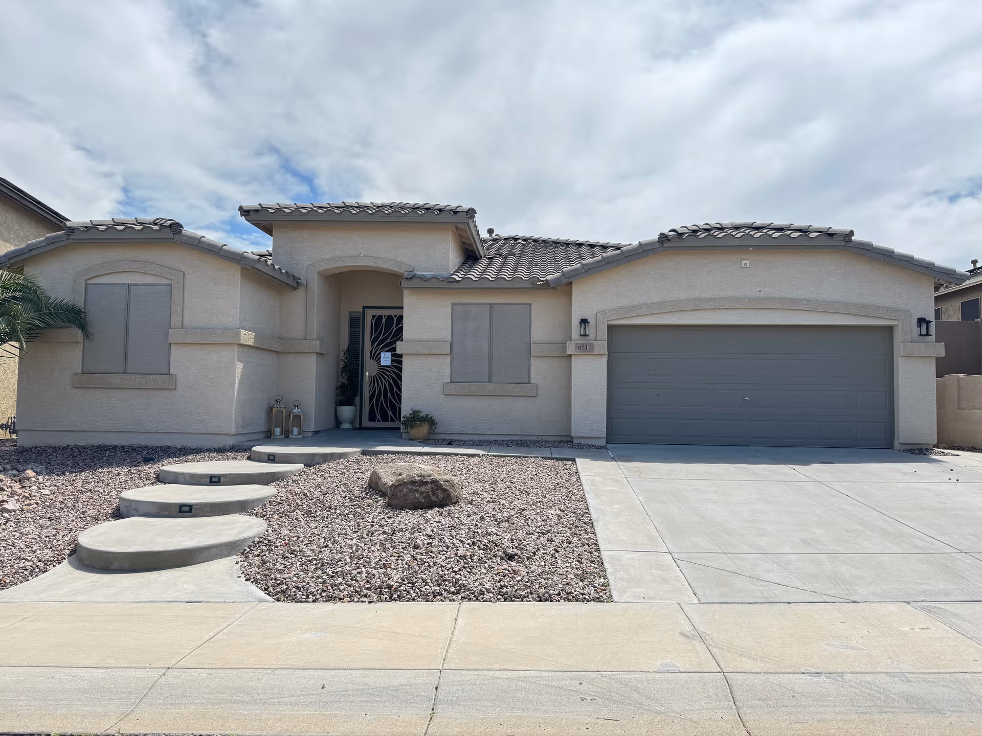 A single-story beige stucco building with a two-car garage and arched front entry.