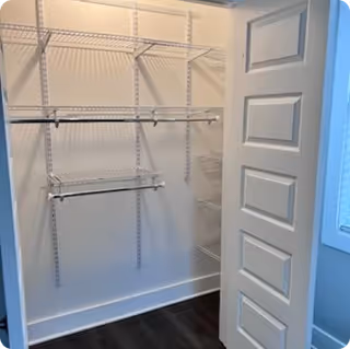 Open closet with metal shelves, hanging rods, and white walls inside a home.