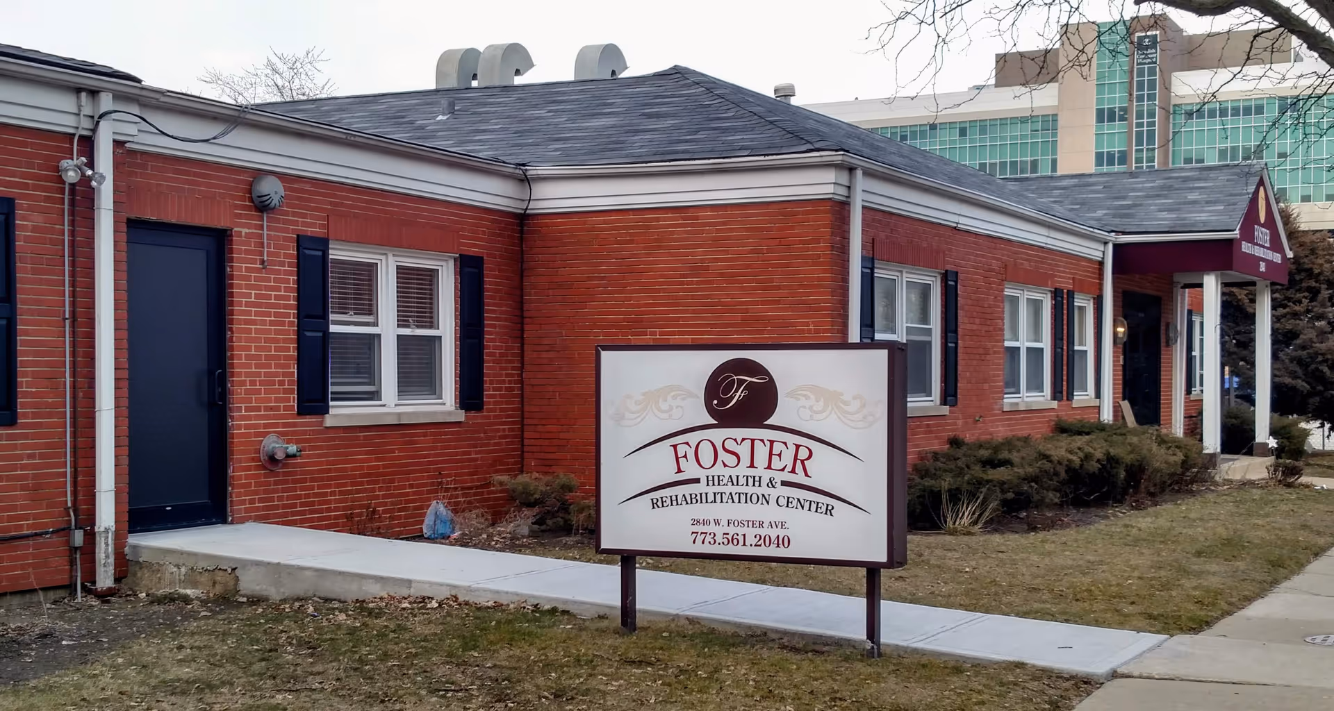 Exterior view of a single-story red brick facility with Foster Health & Rehab sign.