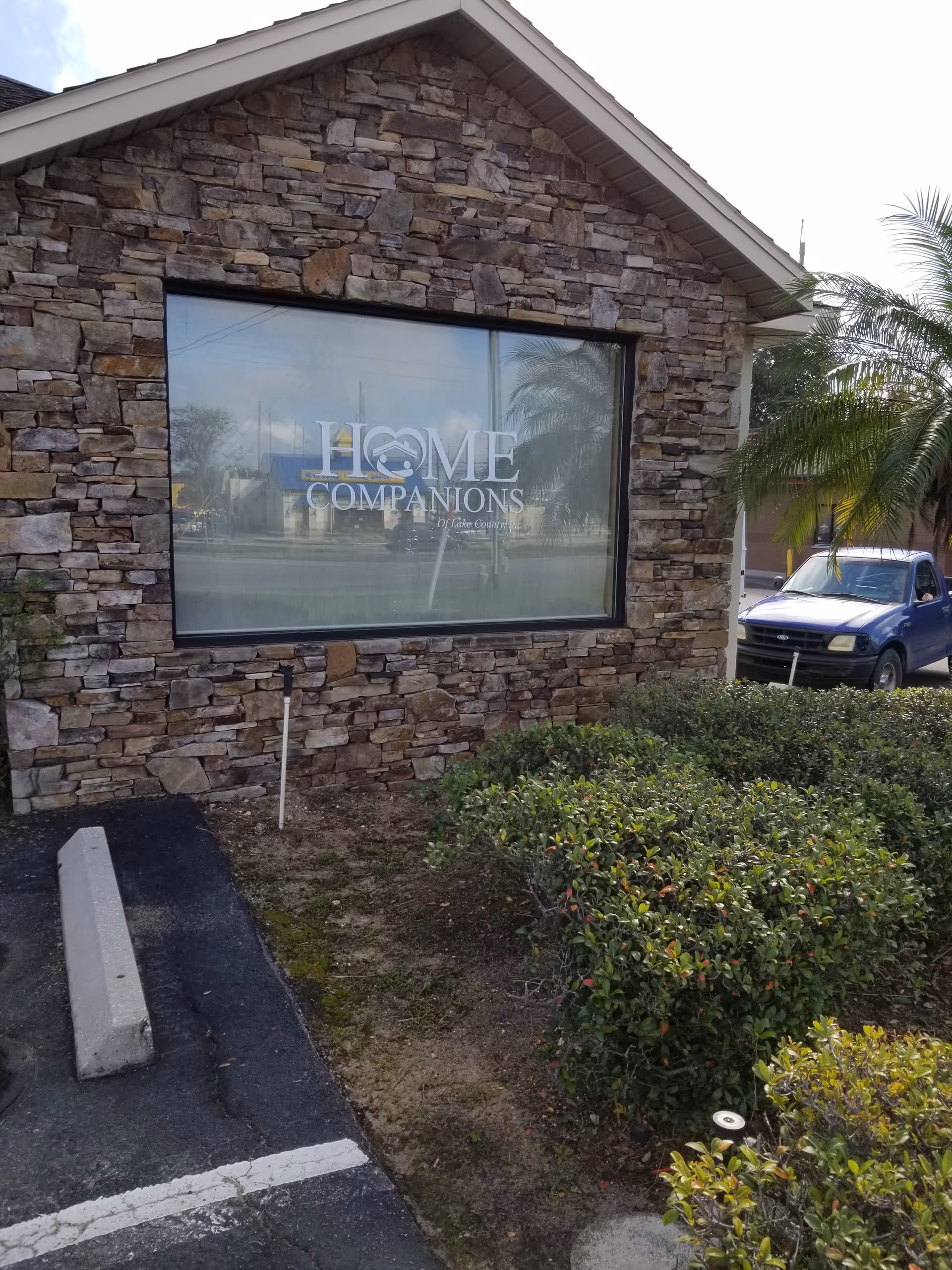 Exterior view of a stone building with a large window sign reading Home Companions.