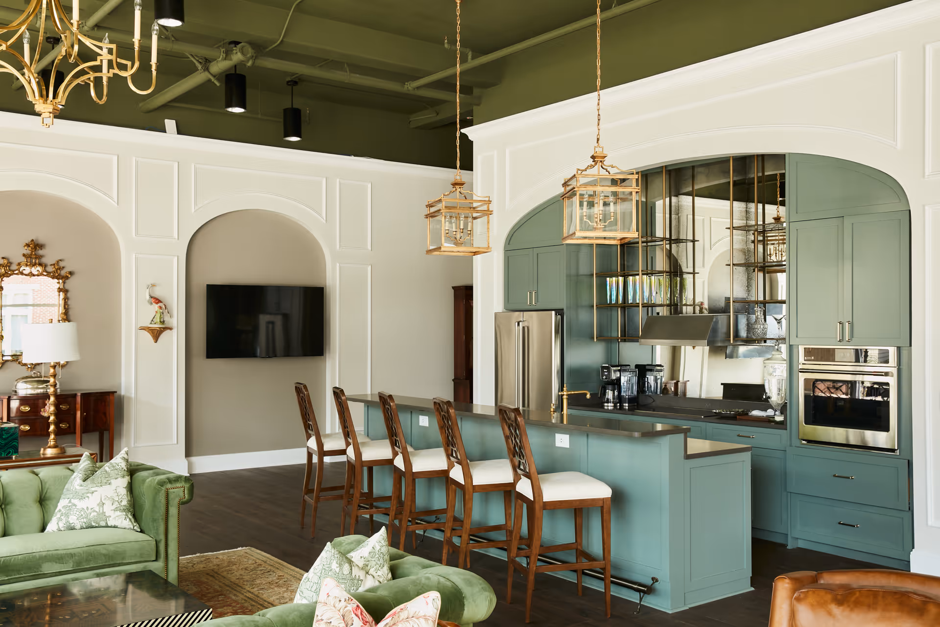 Open-concept kitchen with teal cabinets, island, bar stools, and white paneled walls.