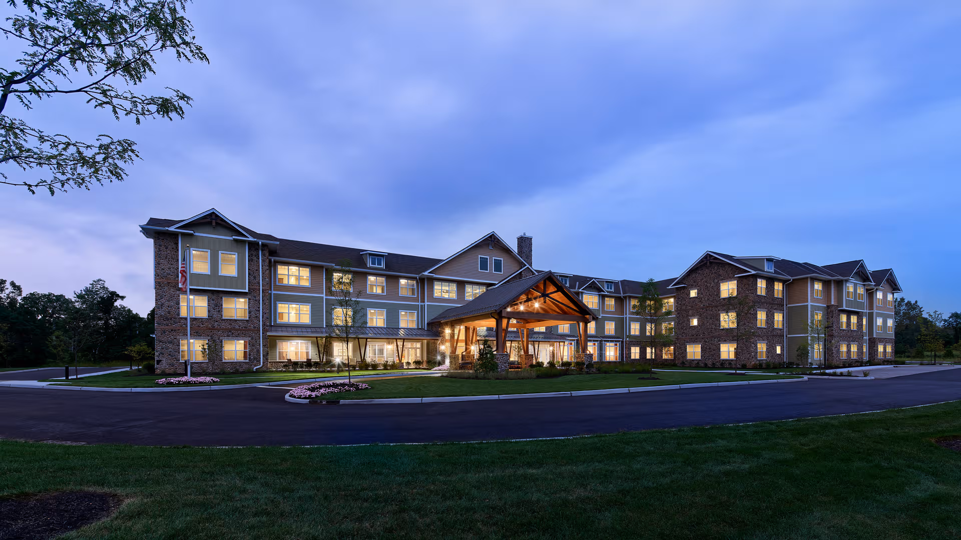 Exterior view of The Chelsea at Greenburgh, with a lit front entrance and brick façade.