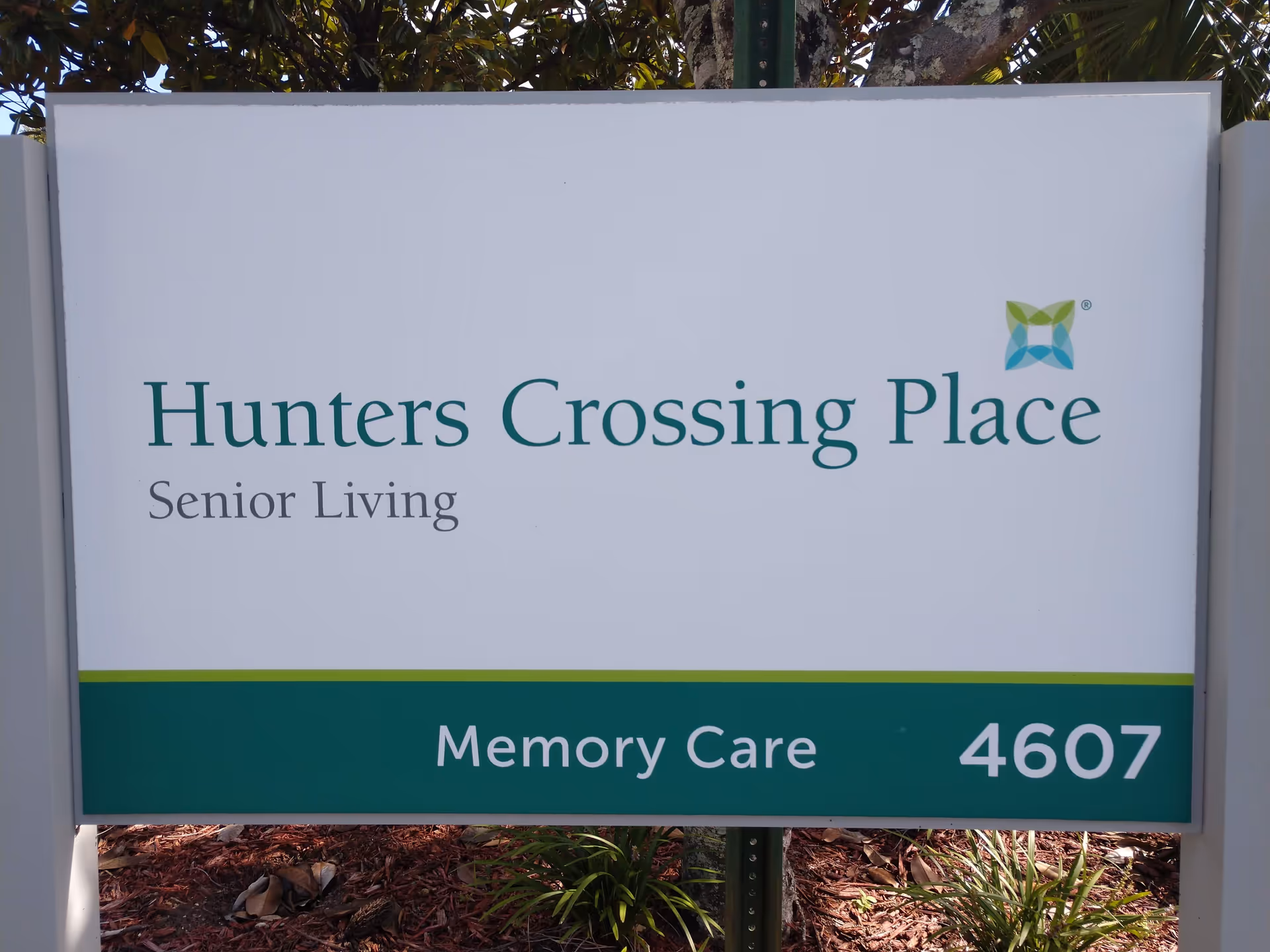Exterior sign reading Hunters Crossing Place Senior Living, Memory Care, with landscaping.
