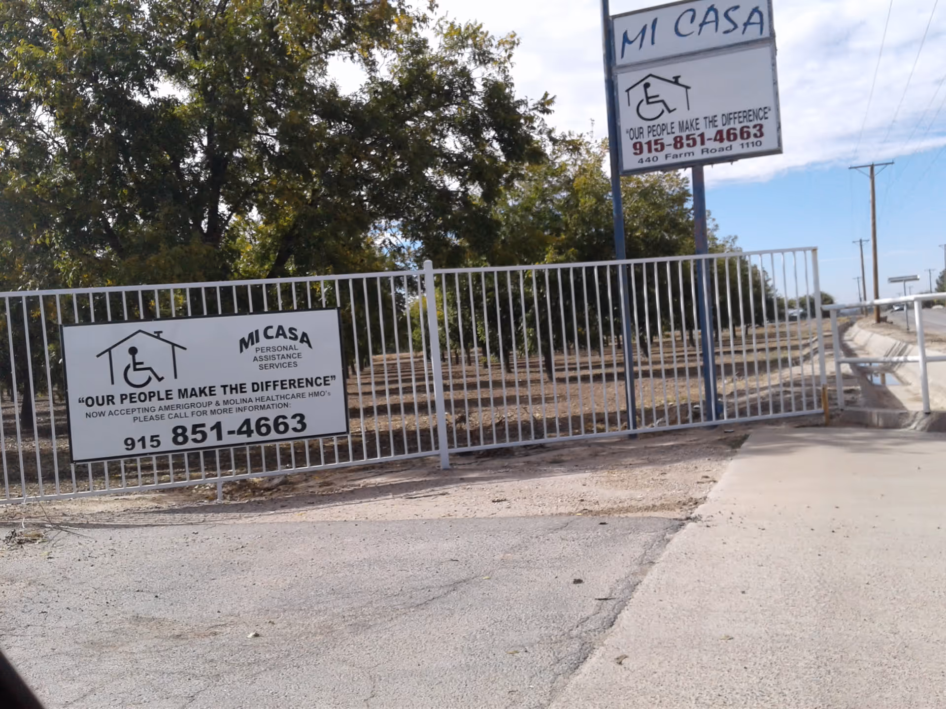 Exterior view of Mi Casa Personal with a gated entrance and large informational signs.