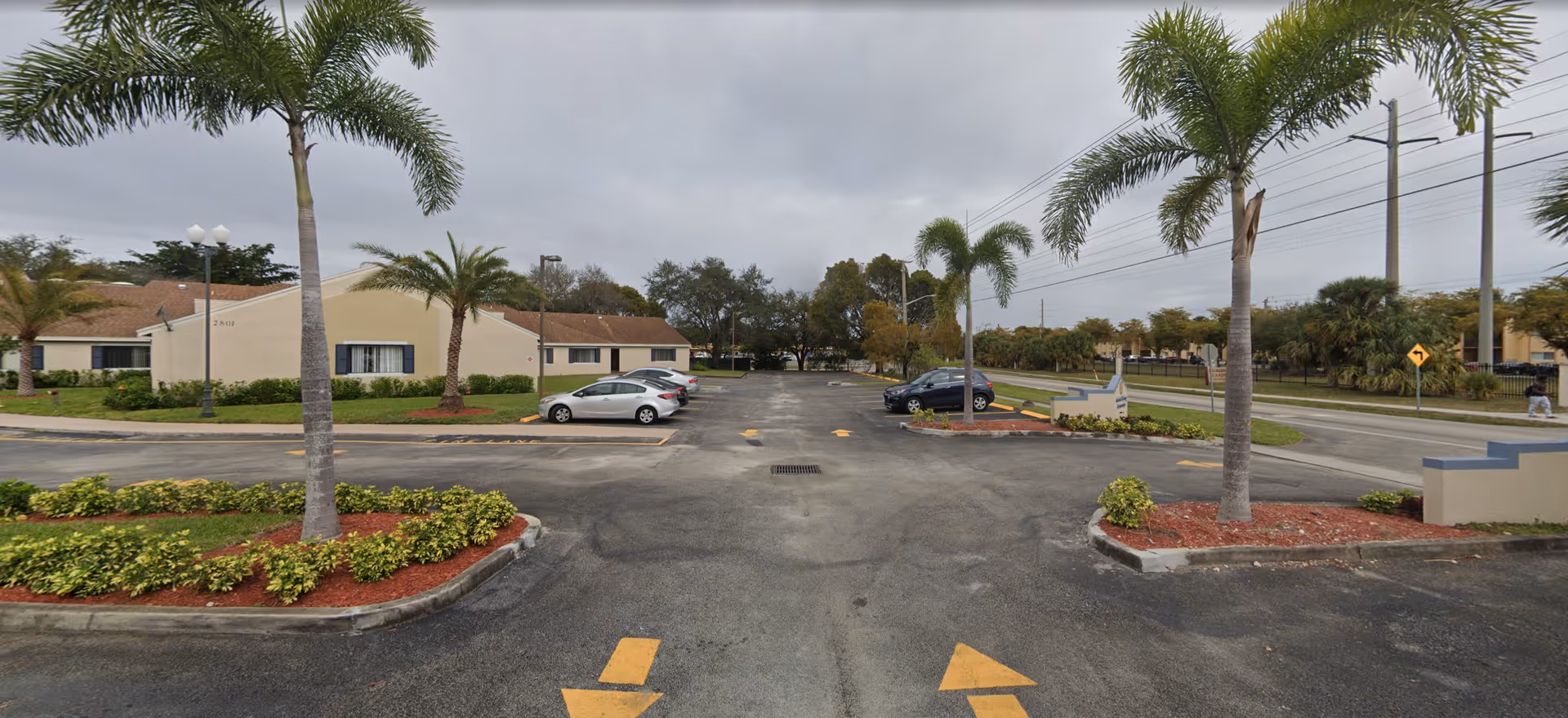 Exterior view of Colonial Assisted Living at Fort Lauderdale with a parking lot and palm trees.