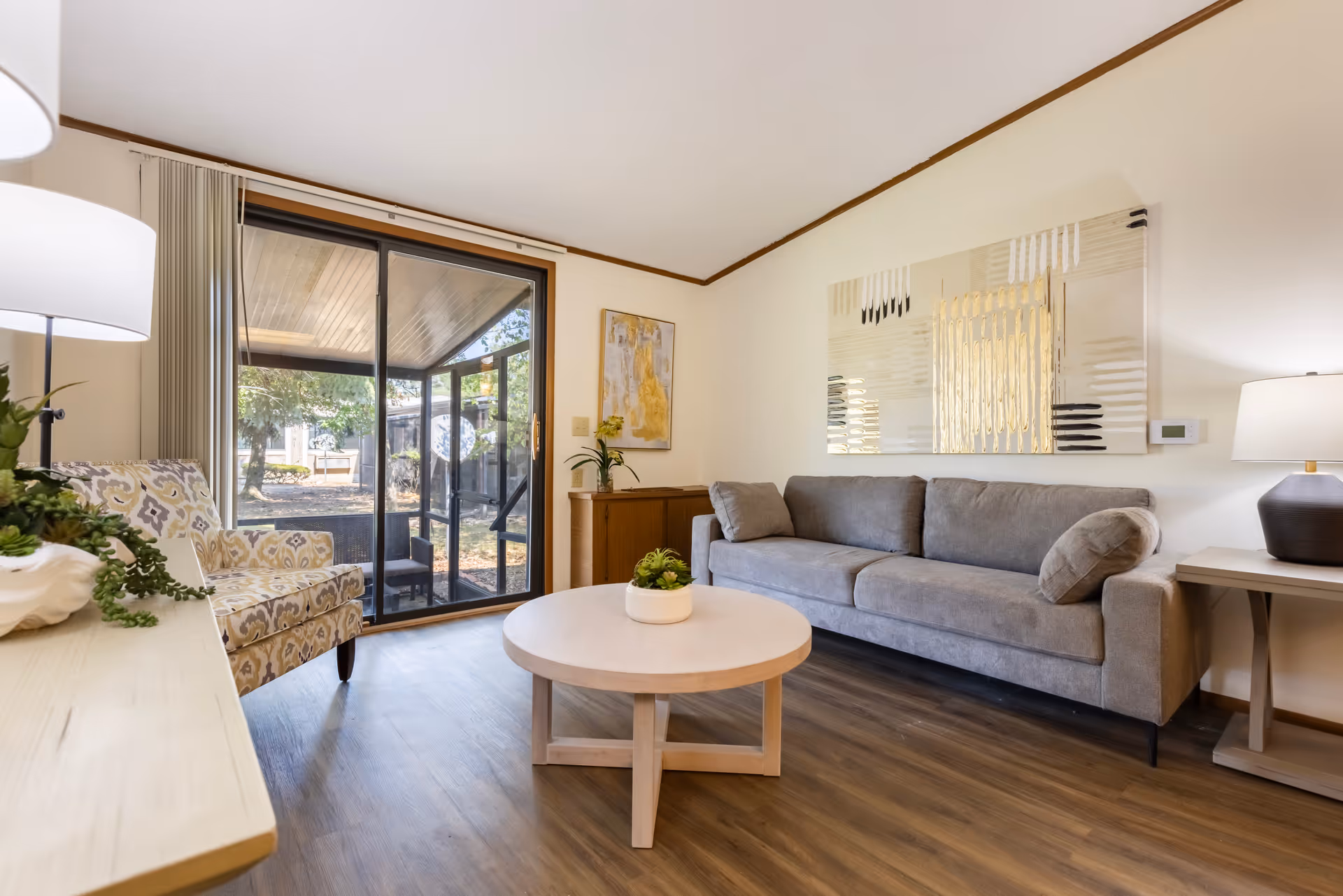 Cozy living room in a senior living facility with a gray sofa and sliding glass door.