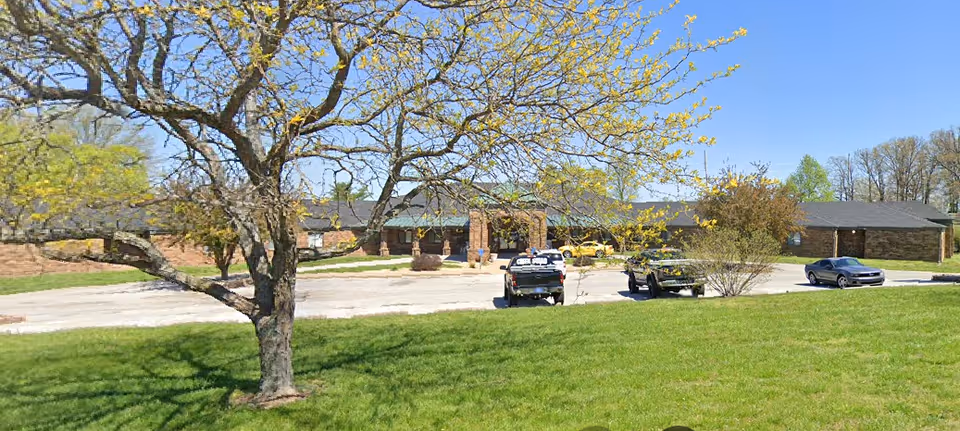 Boulderwood Estates front exterior with parked cars and green lawn.