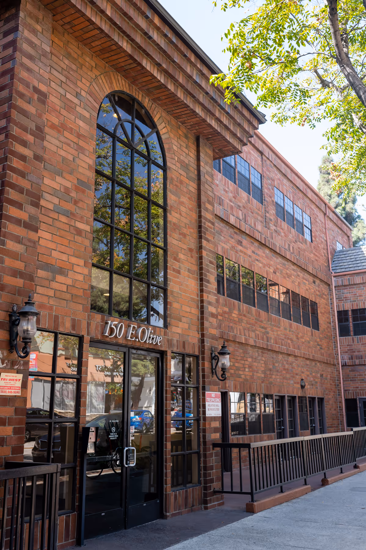 Brick hospice facility exterior with a large arched window and glass entry doors.