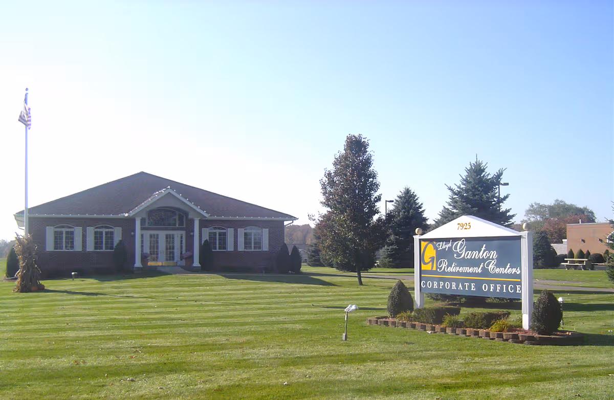 Front exterior of Lloyd Ganton Retirement Centers with a sign on the lawn.