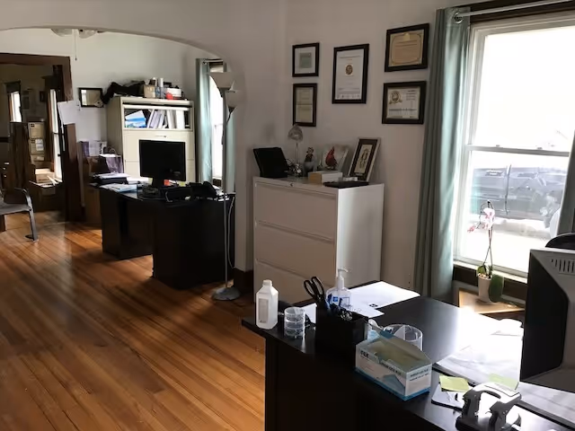 Office area in a senior facility with desks, certificates on wall, and a window.