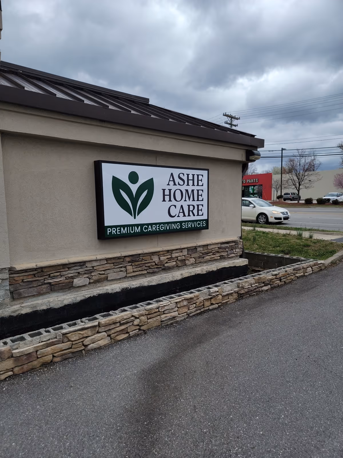 Exterior view of Ashe Home Care building with sign and stone veneer wall.