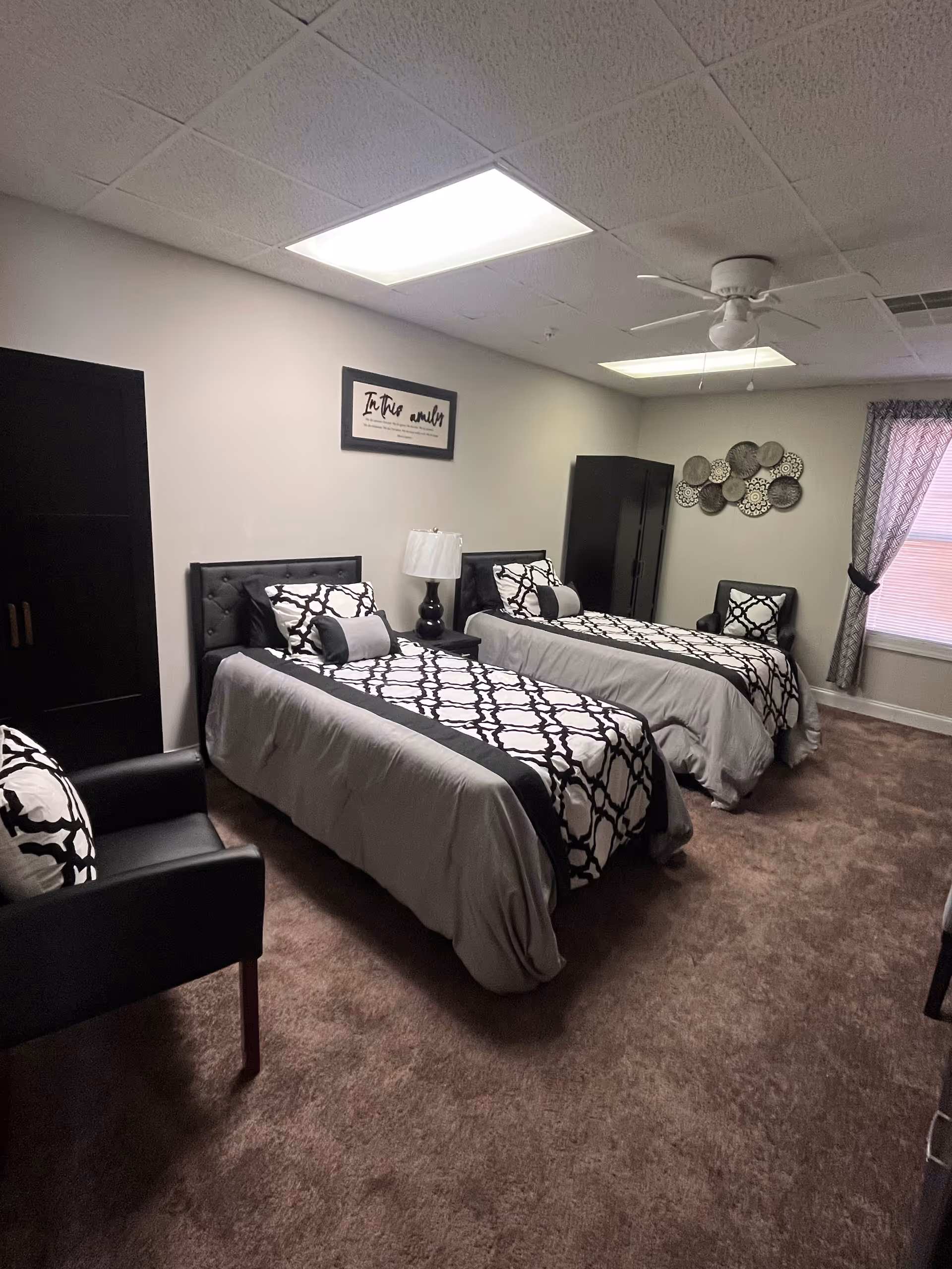 Two twin beds with matching black-and-white patterned bedspreads in a furnished bedroom.