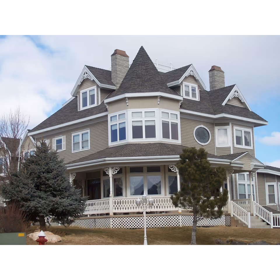 A large Victorian-style senior living building with a wraparound porch and decorative gables
