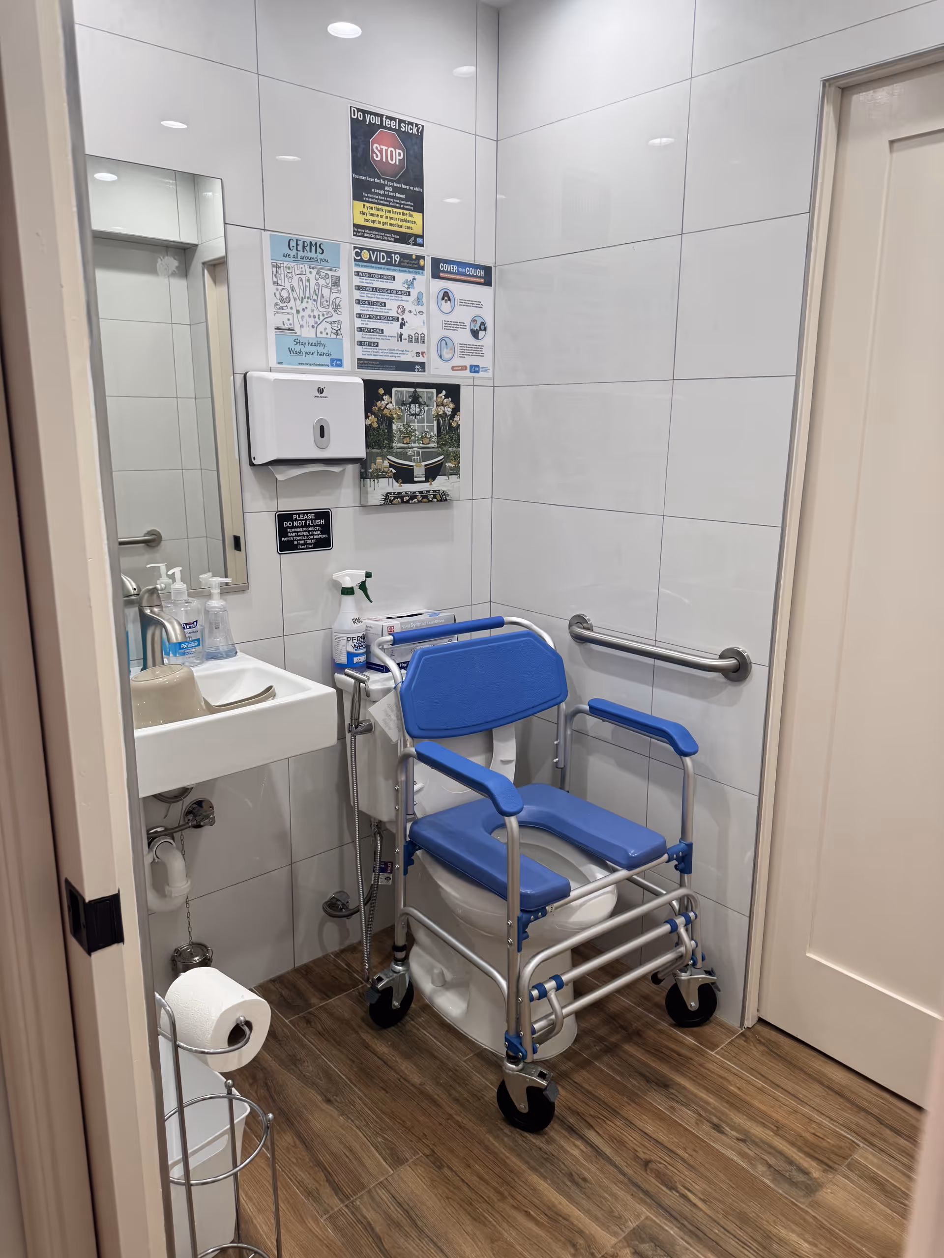 Bright bathroom with a blue shower chair and sink in tile-walled space.