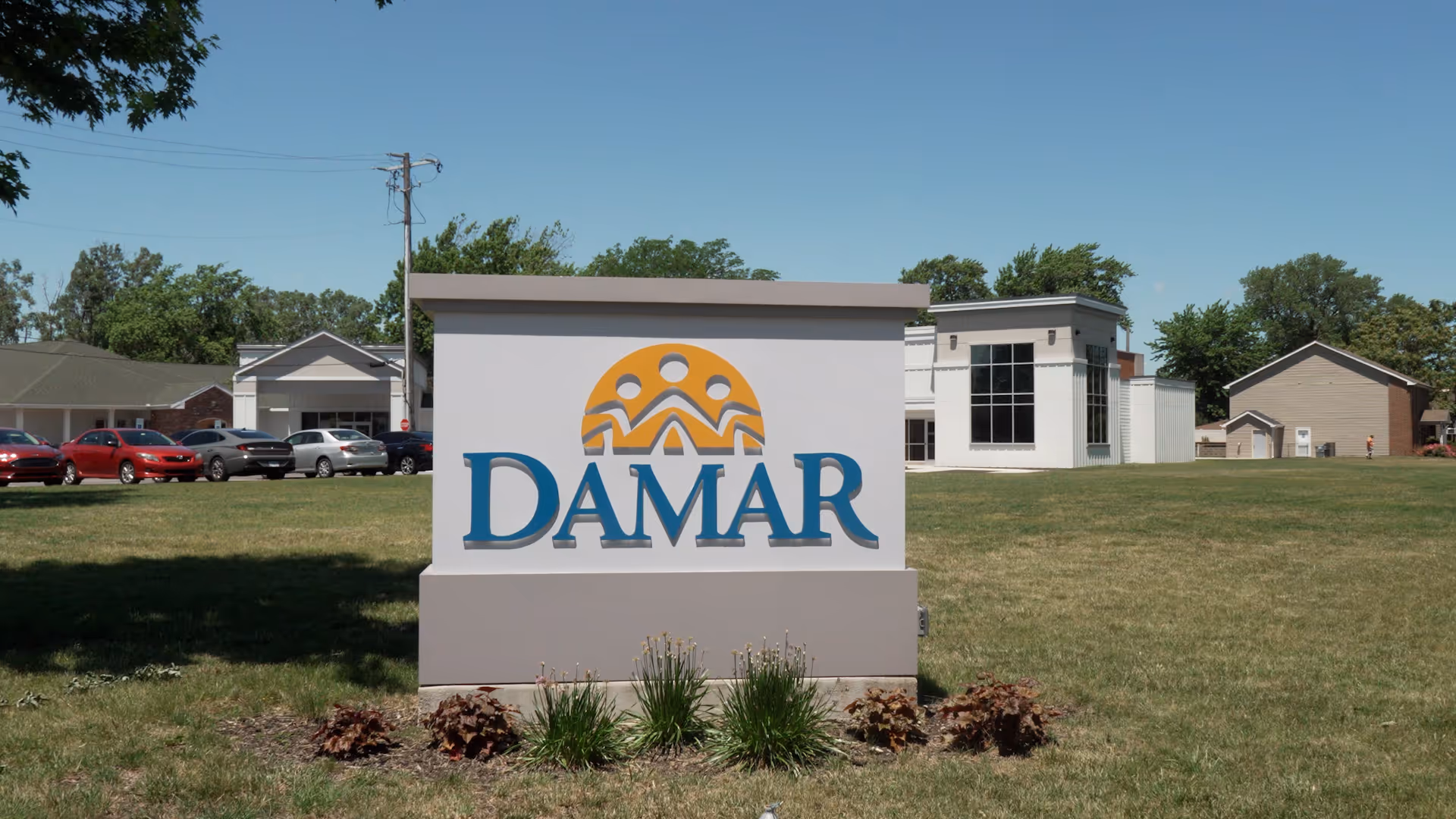 Exterior view of Damar East Chicago facility with a large sign and parked cars.