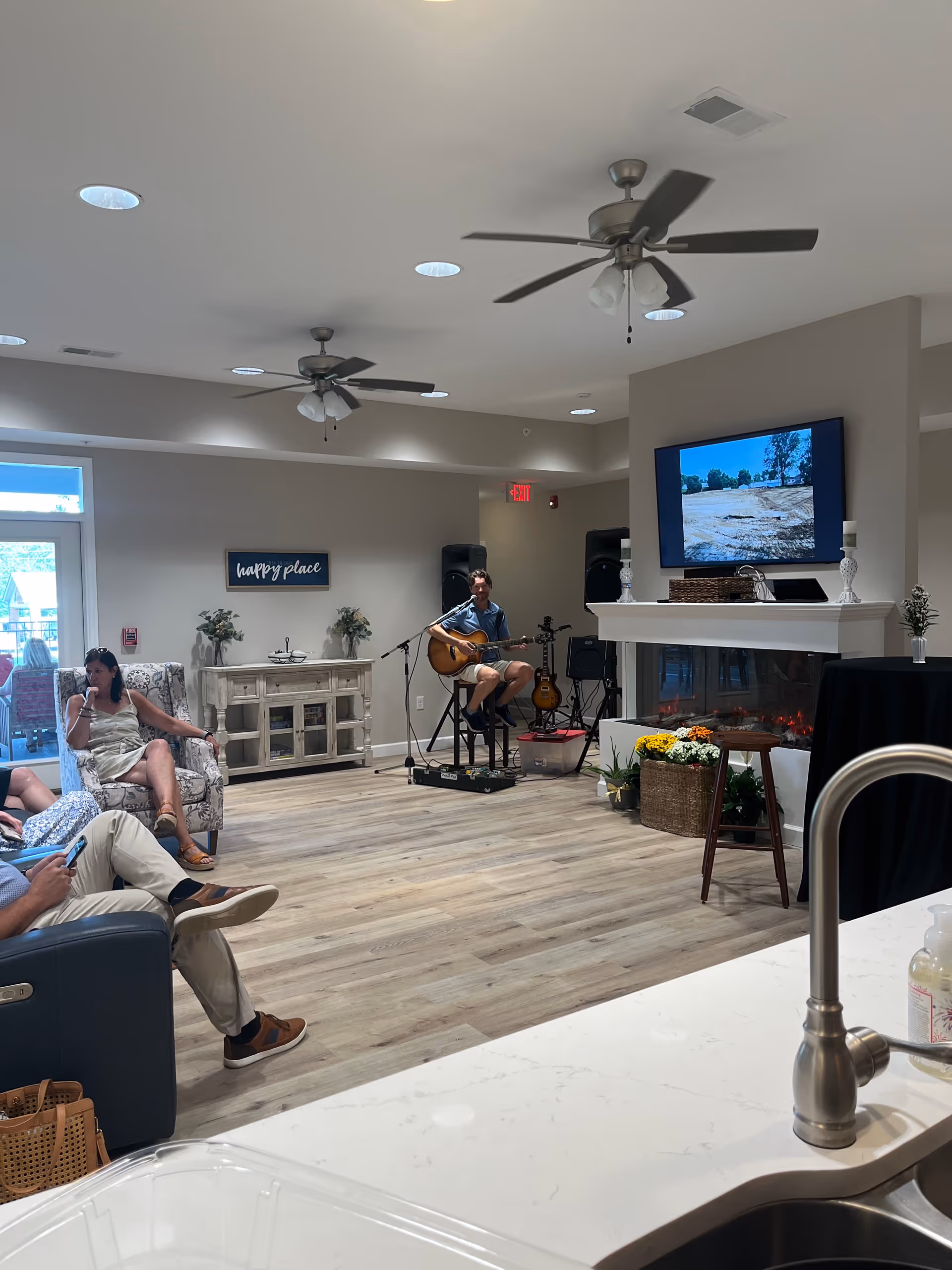 Residents enjoy live guitar music in a cozy Aspen Valley Senior Home living room.