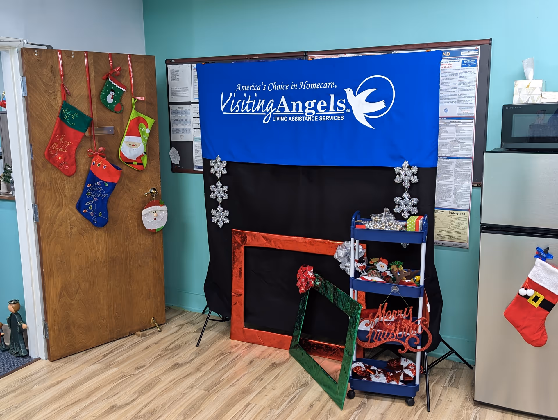 Interior room with blue Visiting Angels banner, holiday decorations, and a display cart.