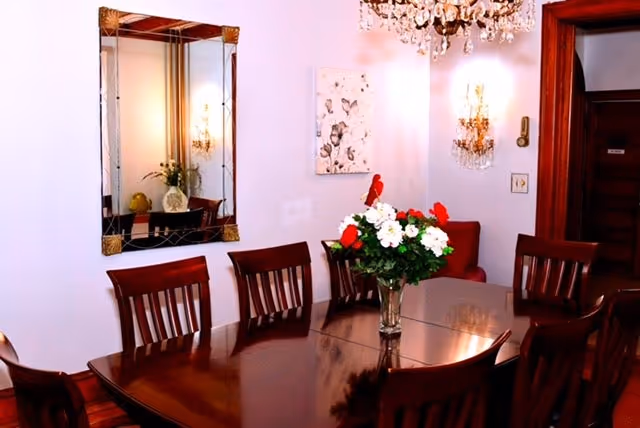 Wood dining table with chairs and chandelier in Serenity Garden Manor dining room.