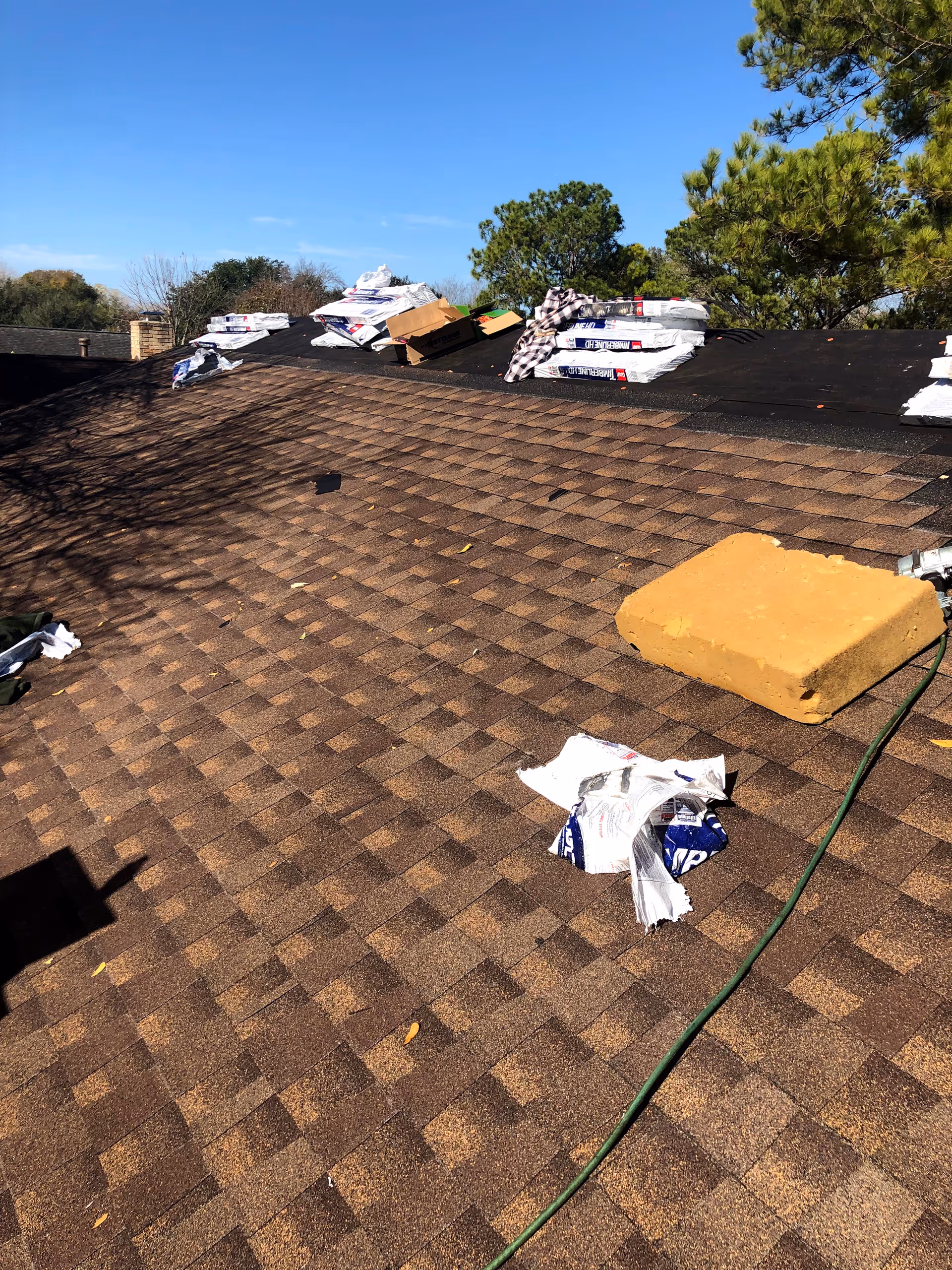 Rooftop with scattered bags, boxes, and debris on shingles under blue sky
