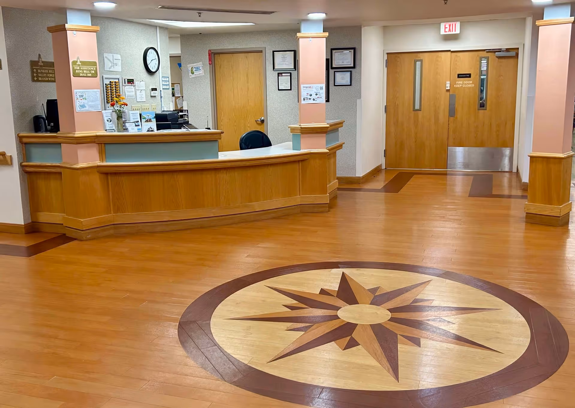 Interior lobby of Independence Court with a curved wooden reception desk and star mosaic floor.