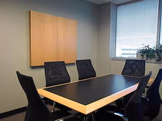Conference room at SeniCare Plus with a large table, six chairs, wall cabinet, and window.
