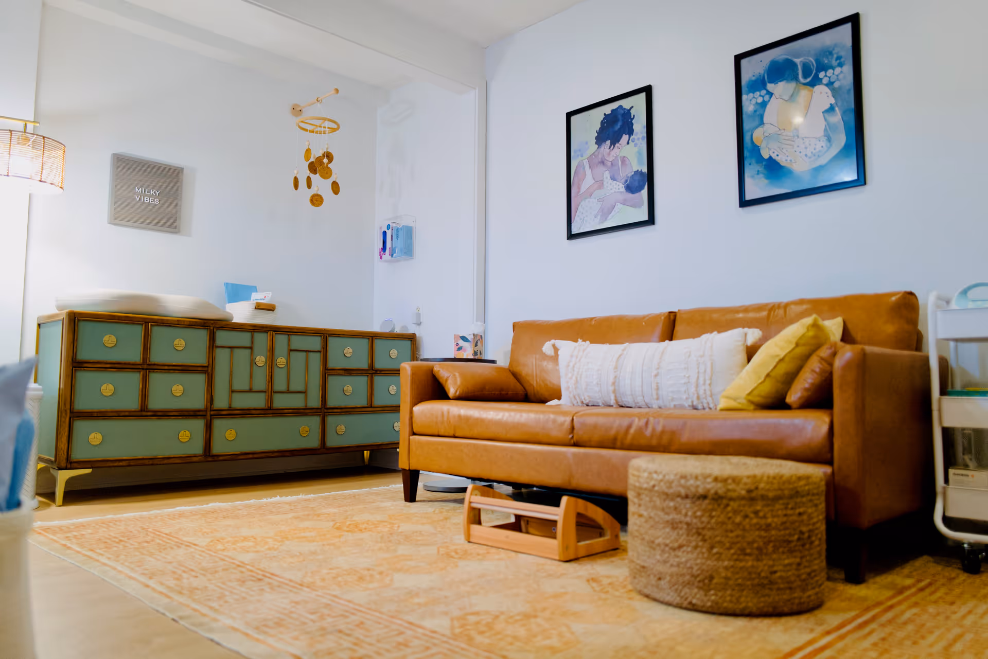 Cozy living room with orange leather sofa, teal dresser, wall art, and soft rug.