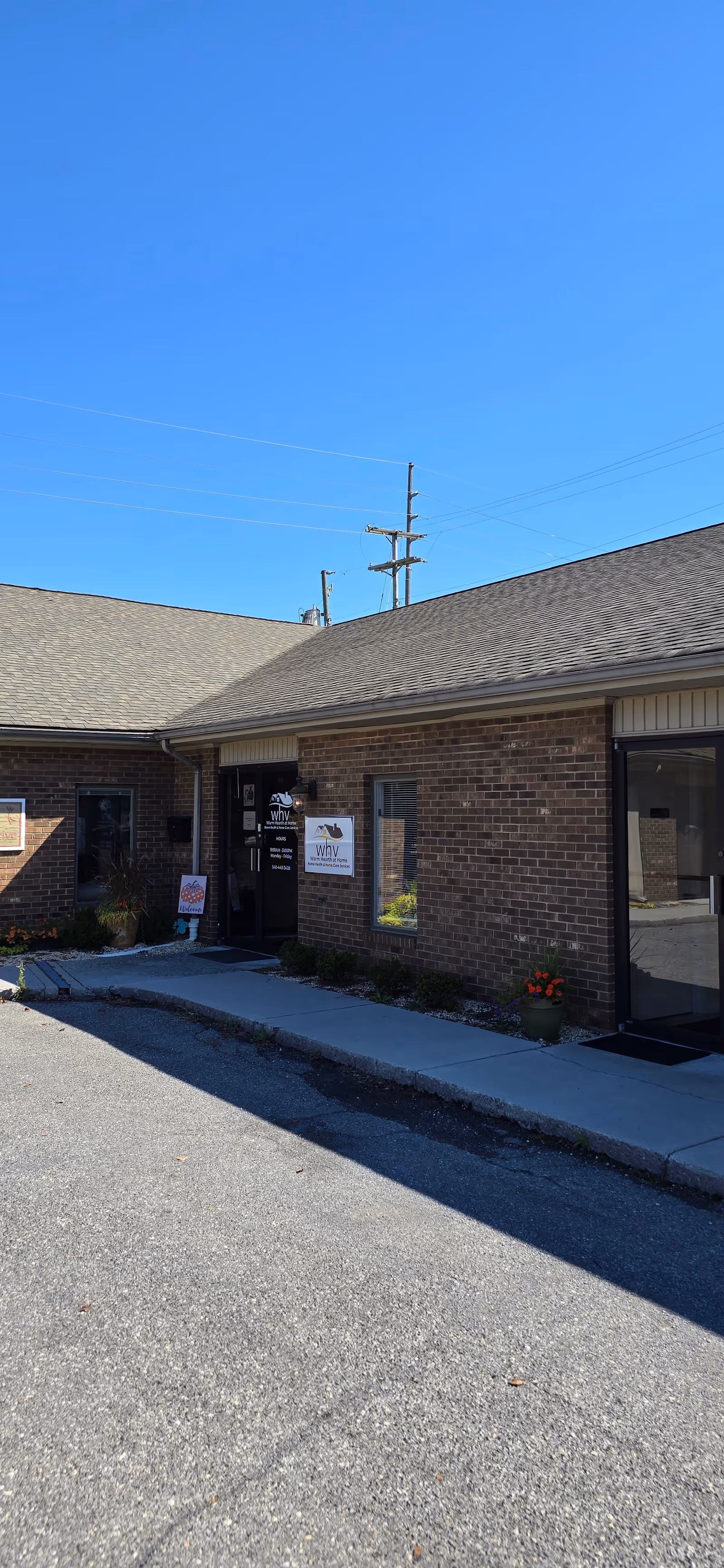 Brick facility entrance with glass door, signs, and a clear blue sky overhead.