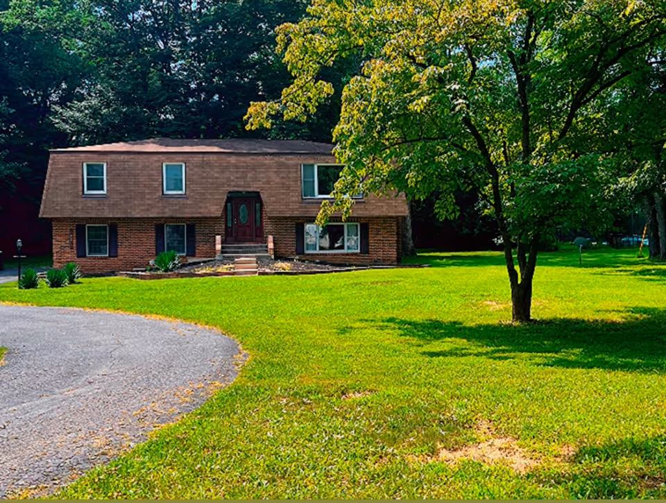 Brick two-story assisted living building with a curved driveway and lush front lawn.