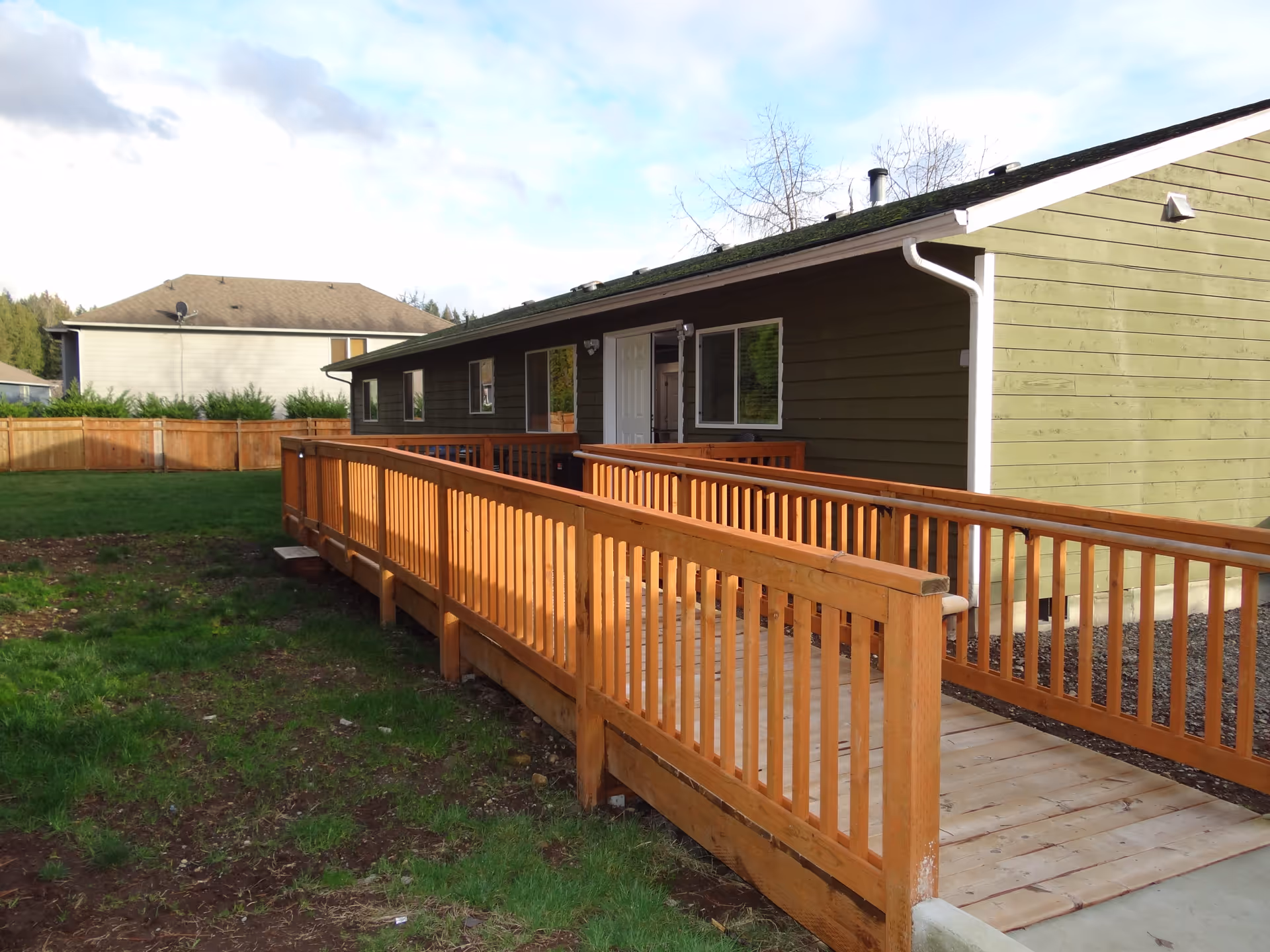 Single-story facility exterior with wooden ramp, green lawn, and fenced yard