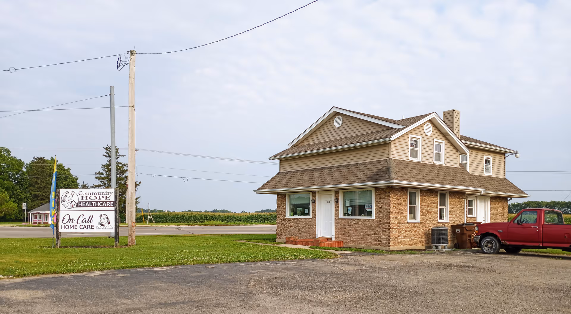 Brick building with front entrance and a sign for Community Hope Healthcare beside a red pickup.