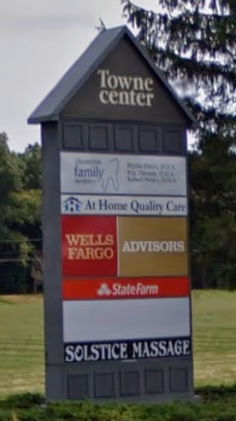 Exterior signboard listing Towne Center and At Home Quality Care with sponsor logos.