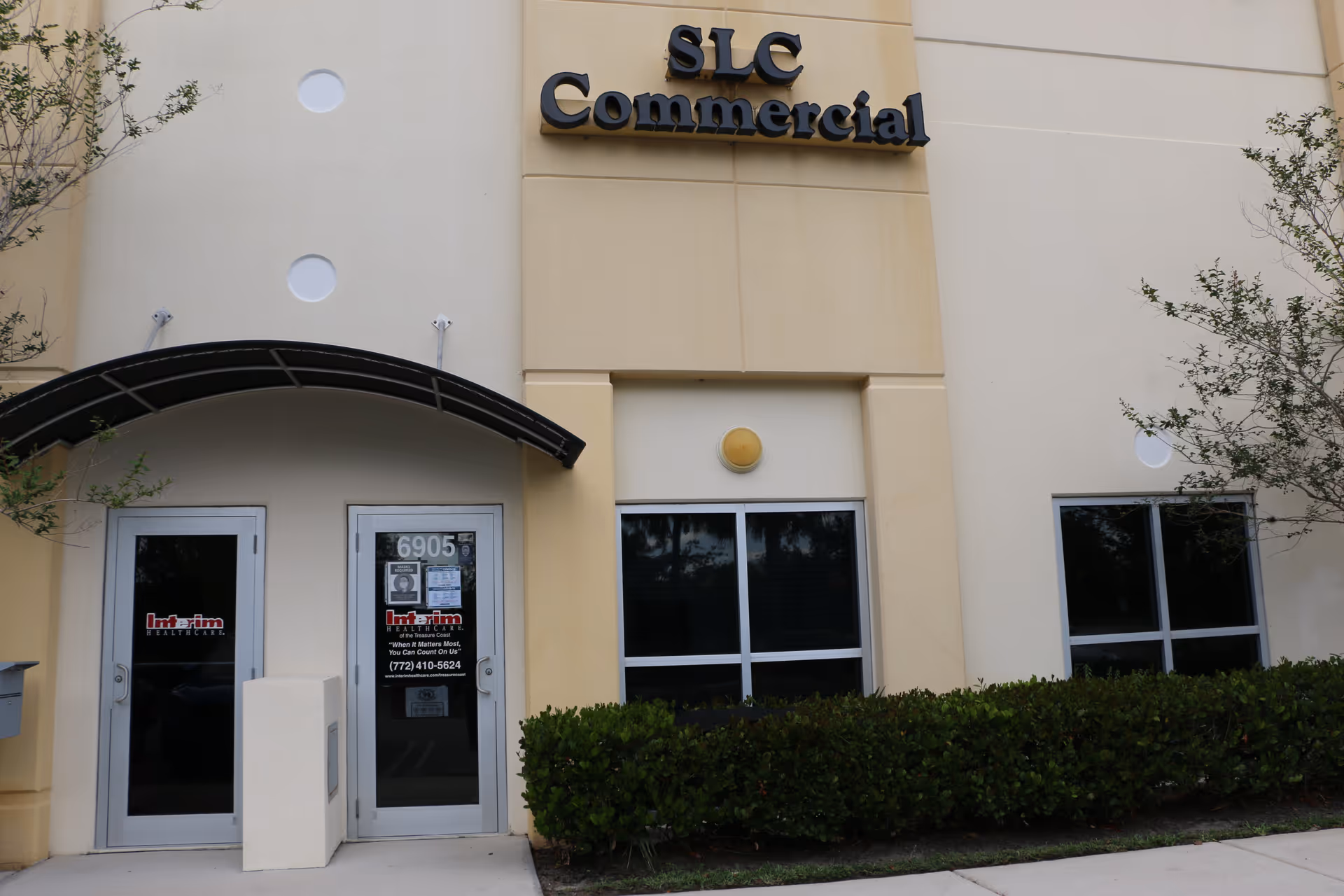 Exterior view of Interim HealthCare entrance with glass doors and SLC Commercial signage