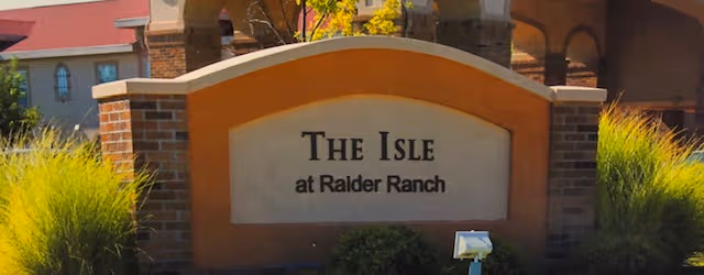 Entrance sign for The Isle at Raider Ranch with brick columns and landscaping.