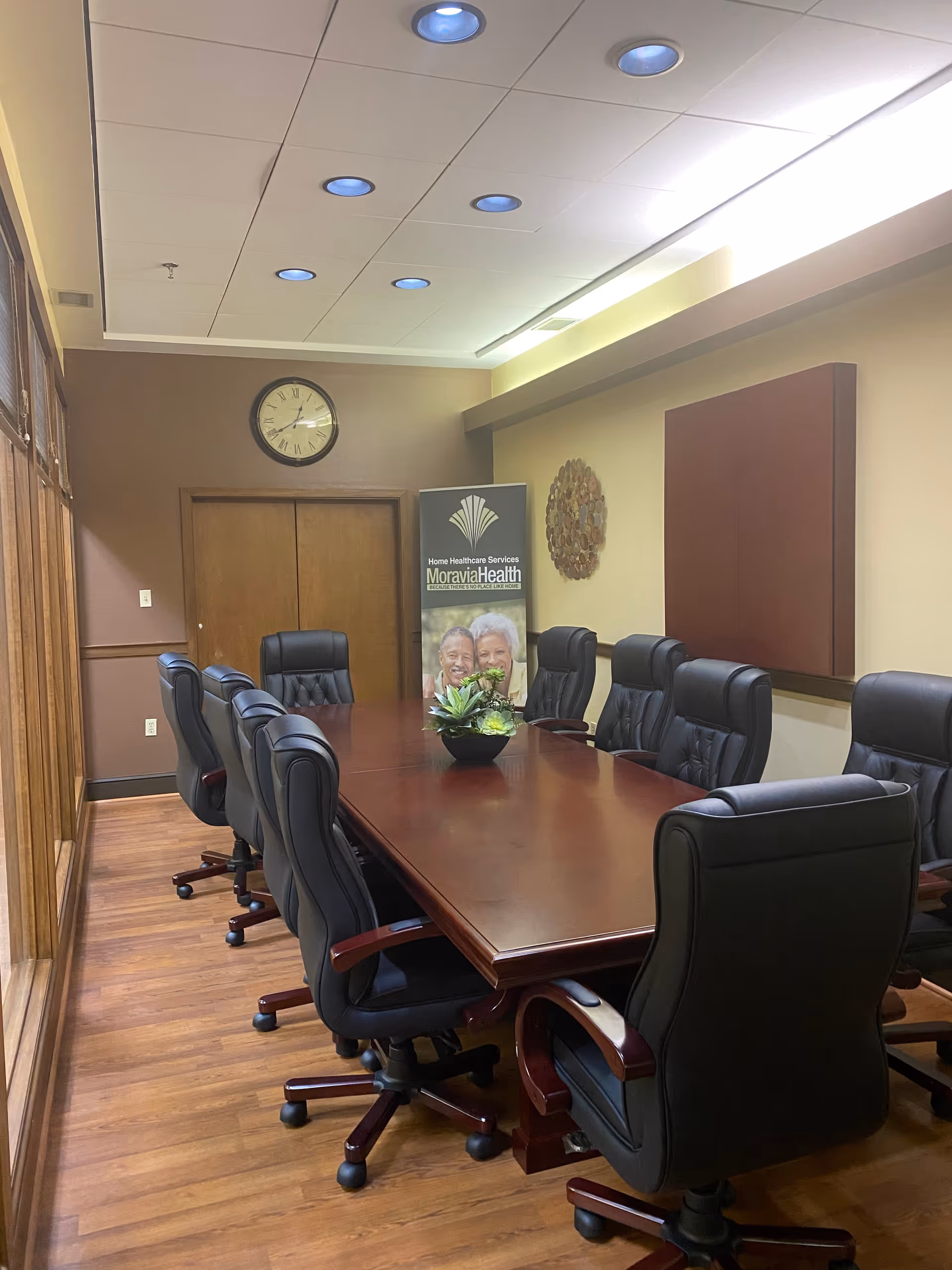 A long conference table with black leather chairs around a formal meeting room.