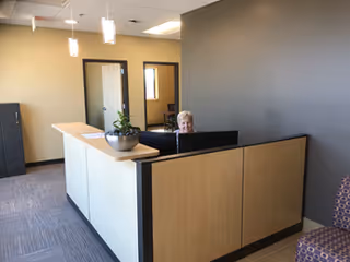 Reception desk in a modern lobby with a smiling staff member.