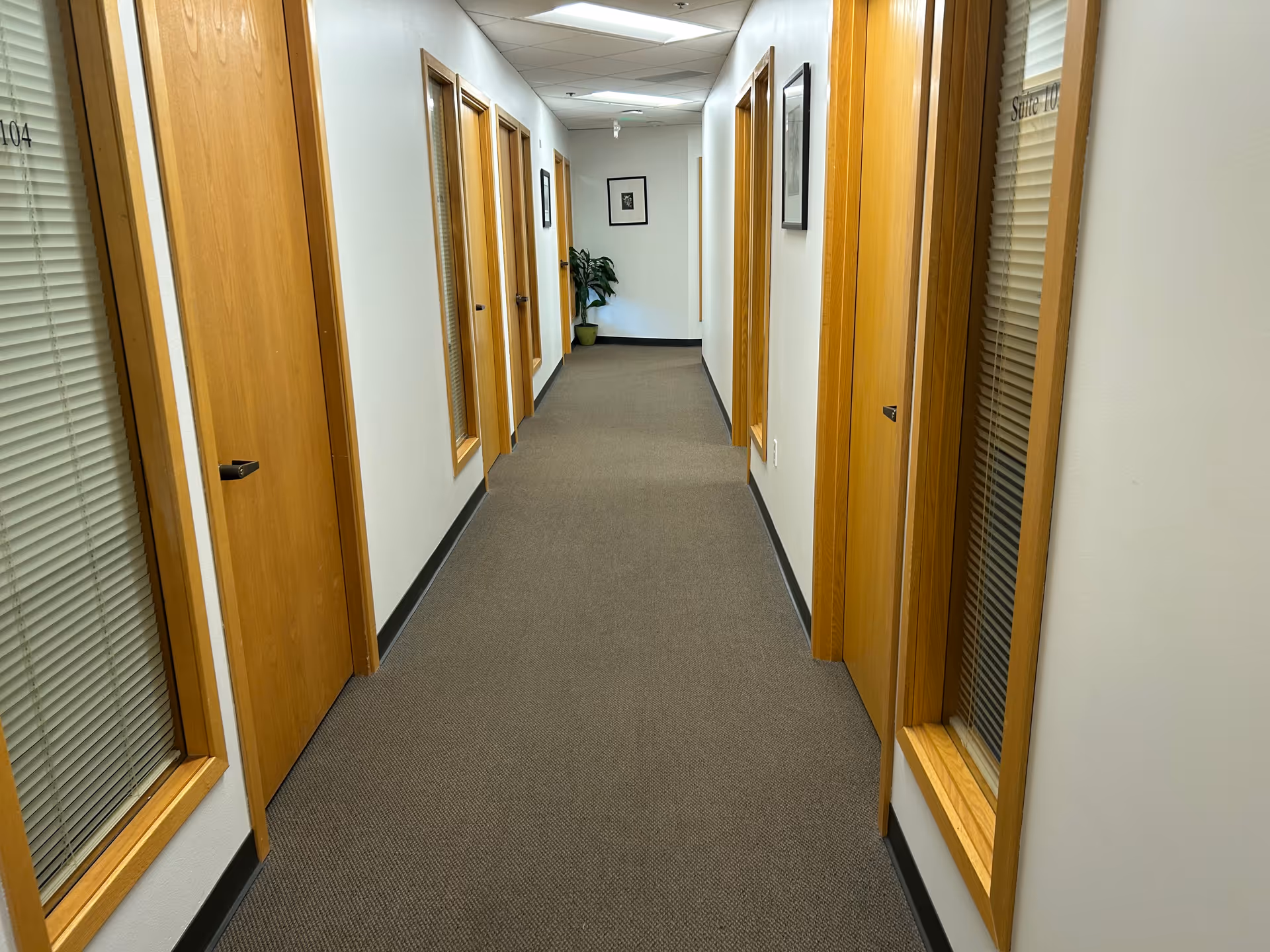 A quiet indoor corridor in a senior living facility with wooden doors.
