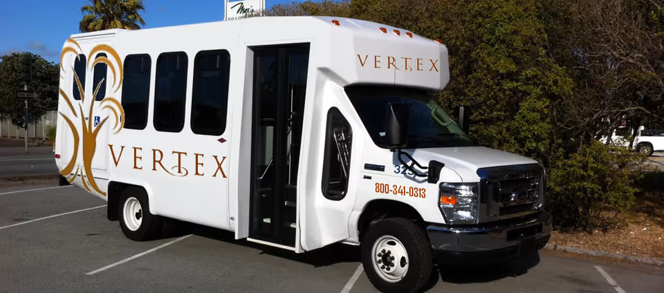 White Vertex Senior Living Solutions shuttle van parked in a lot with open side door.