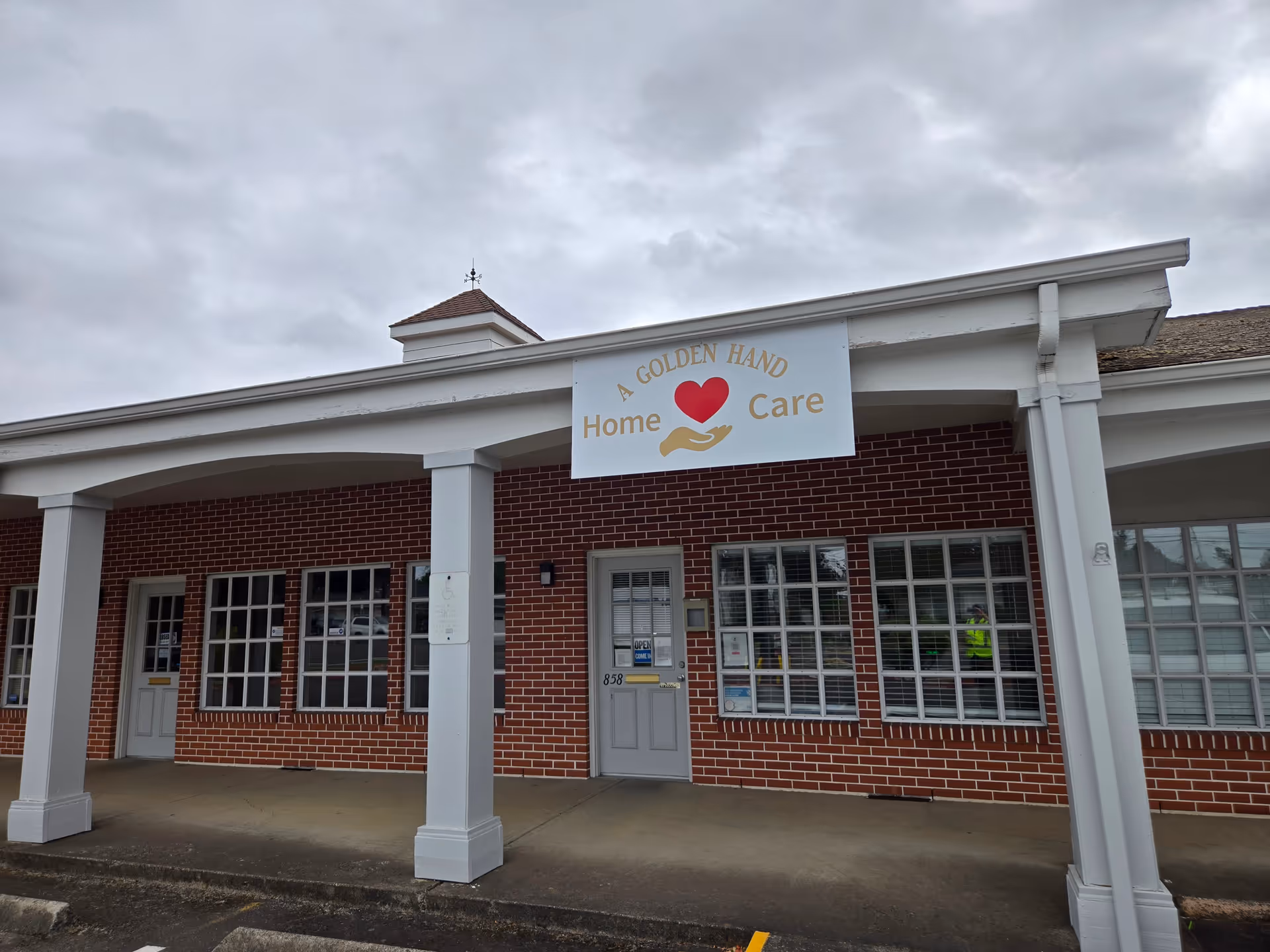 Brick-faced facility with a white columned entrance and a sign reading A Golden Hand Home Care.