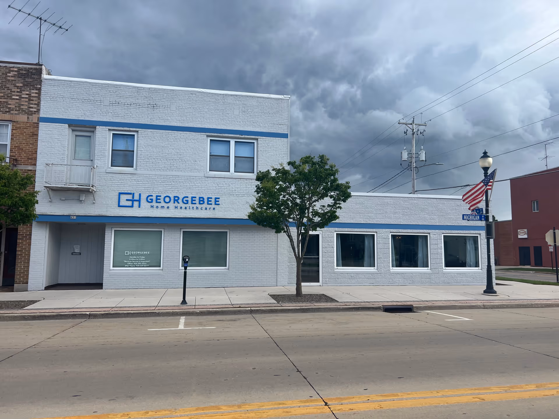 Georgebee Home Healthcare building on a street with a tree, flag, and sidewalk.