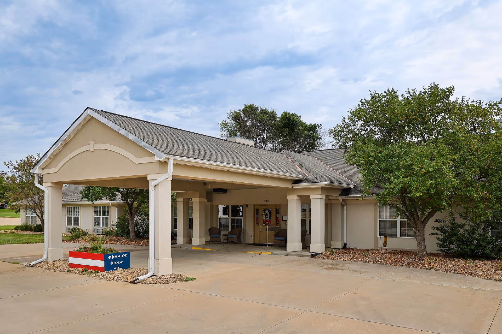 Vintage Park at Holton entrance with a covered drive, columns, and surrounding trees.
