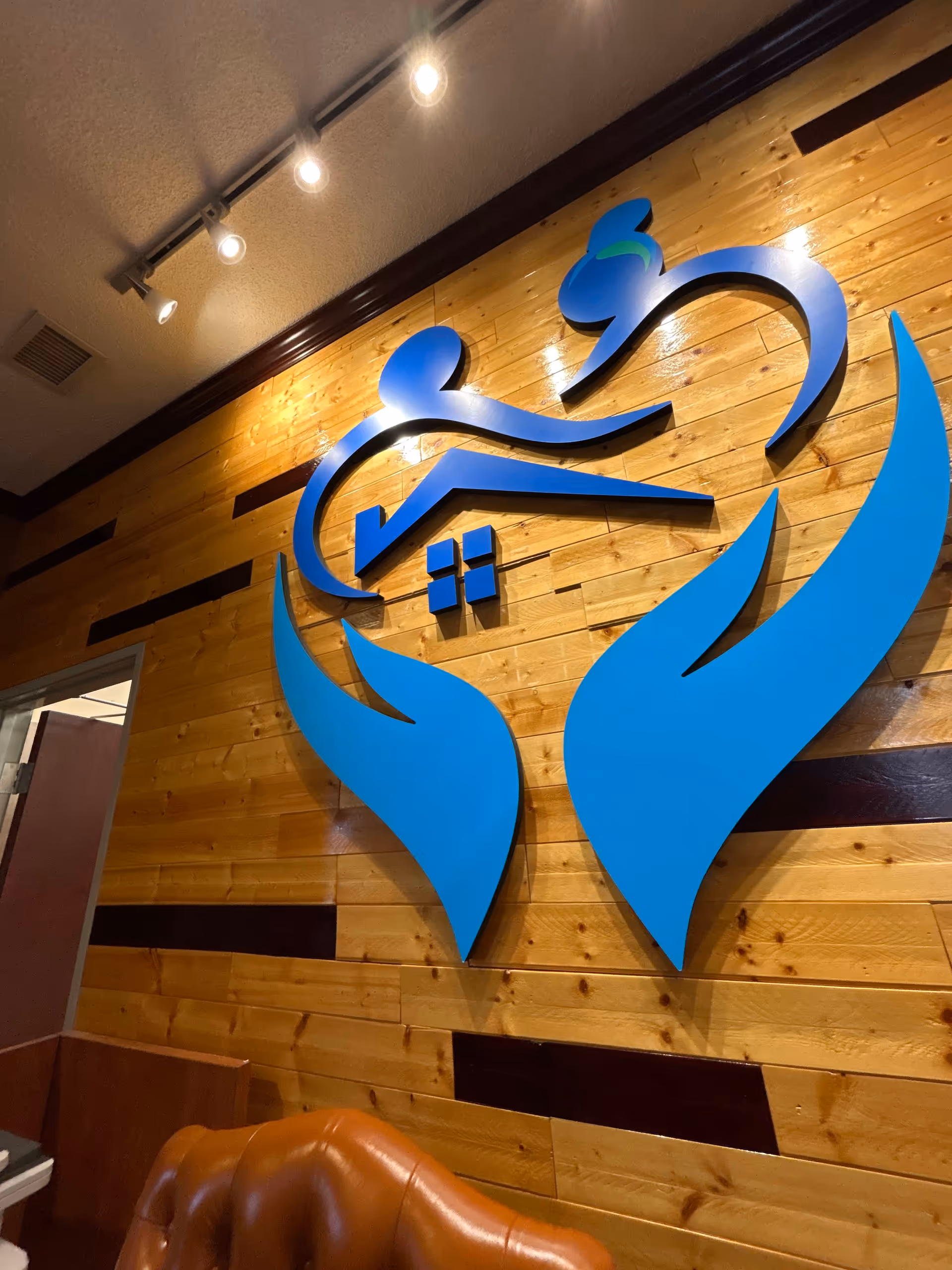 Blue abstract care logo mounted on wooden wall inside facility lobby