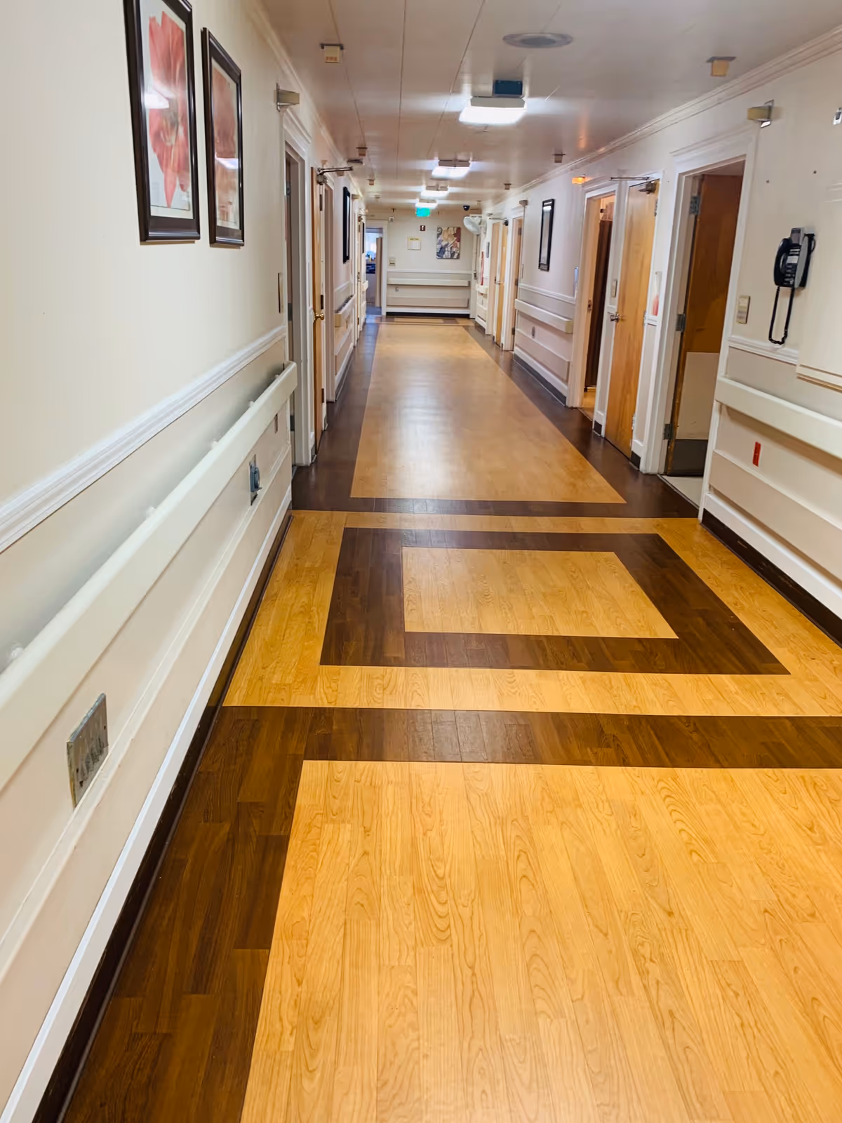 Long interior corridor at Arden Park Post Acute with wood-pattern floors and framed art.