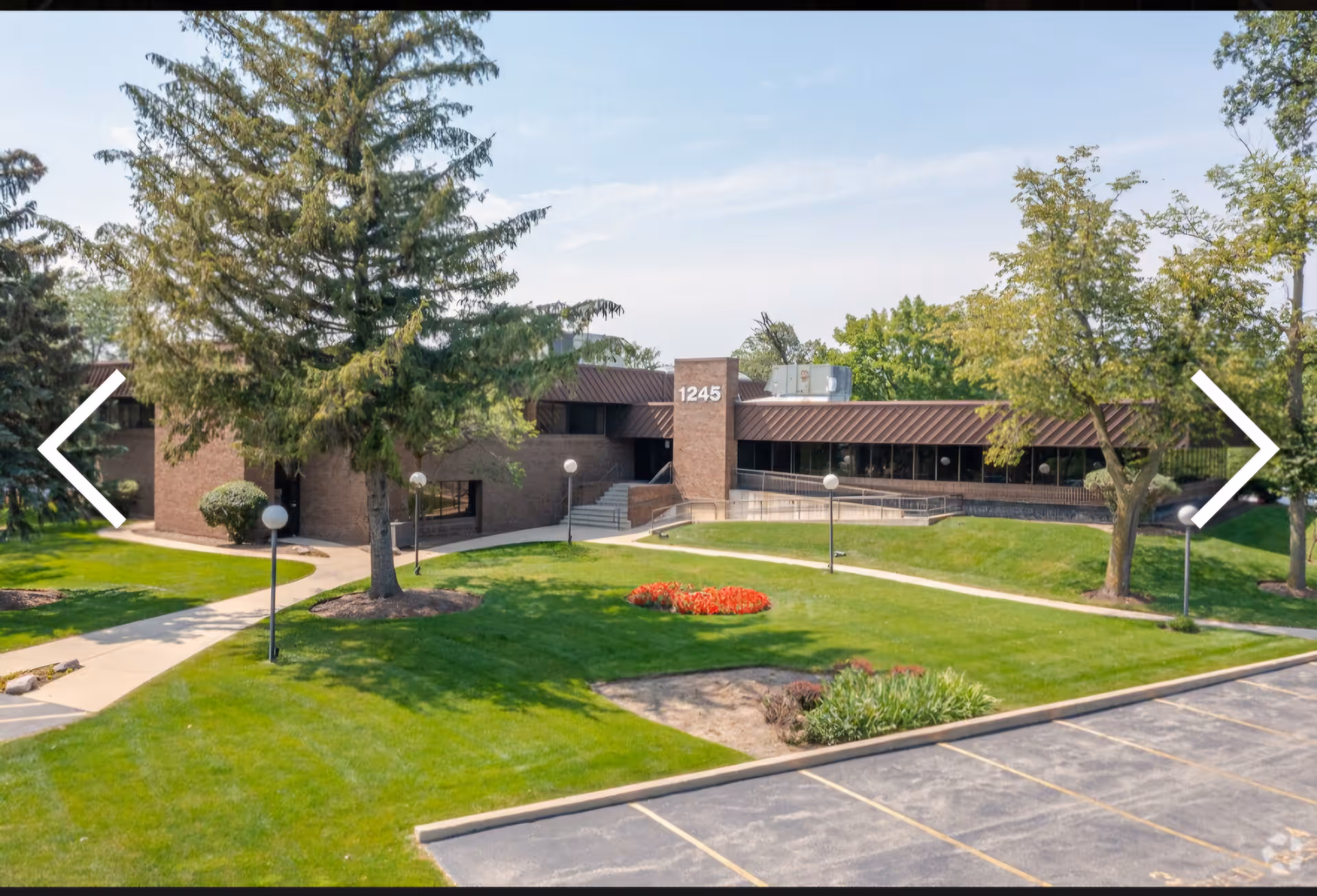 Exterior front of a brown brick senior facility with green lawn and walkway