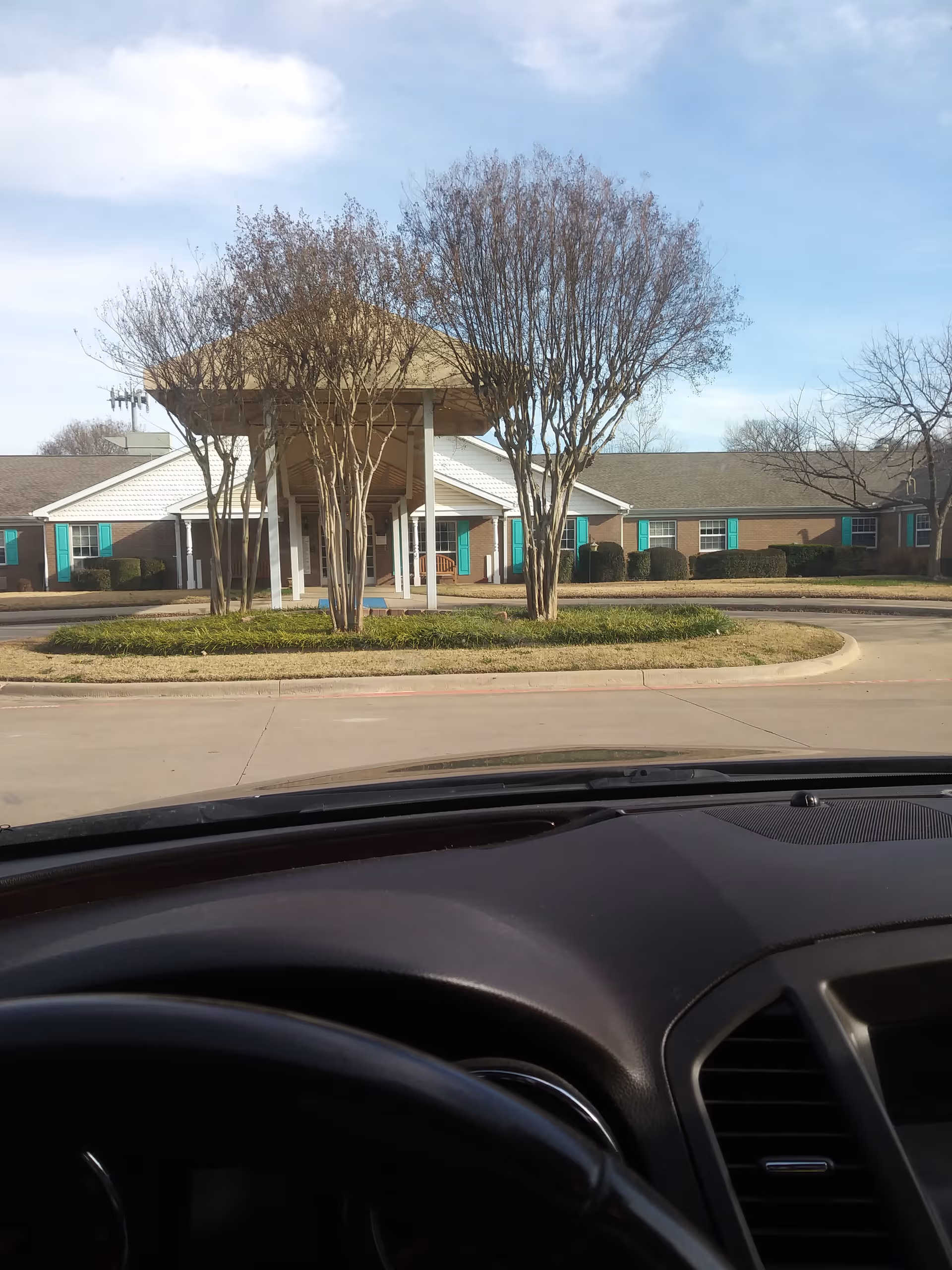 Front view of a memory care facility with a covered entrance and circular driveway.