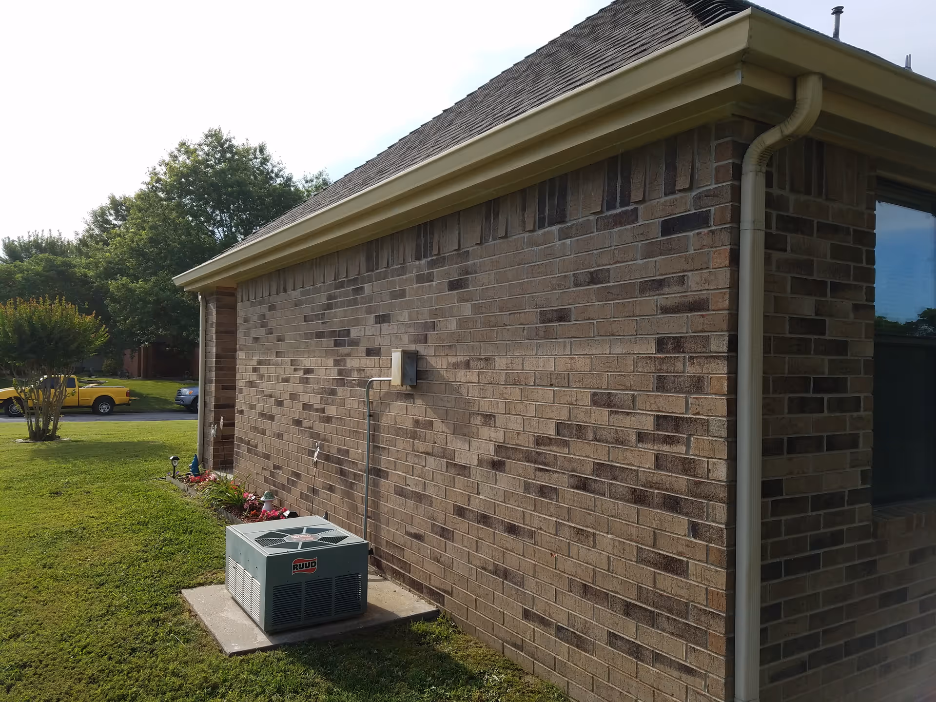 Brick exterior of a facility with an air conditioner unit and a green lawn.
