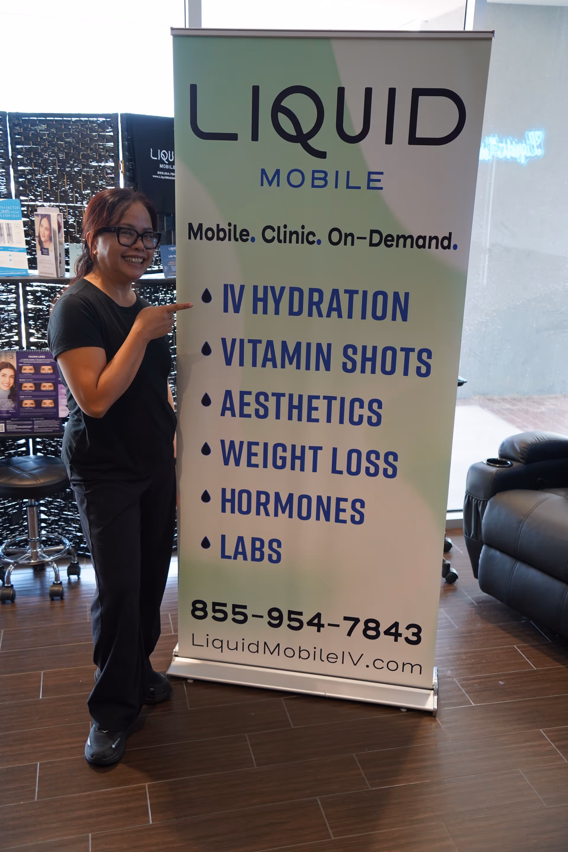 Staff member stands beside a Liquid Mobile IV banner inside a facility lobby.