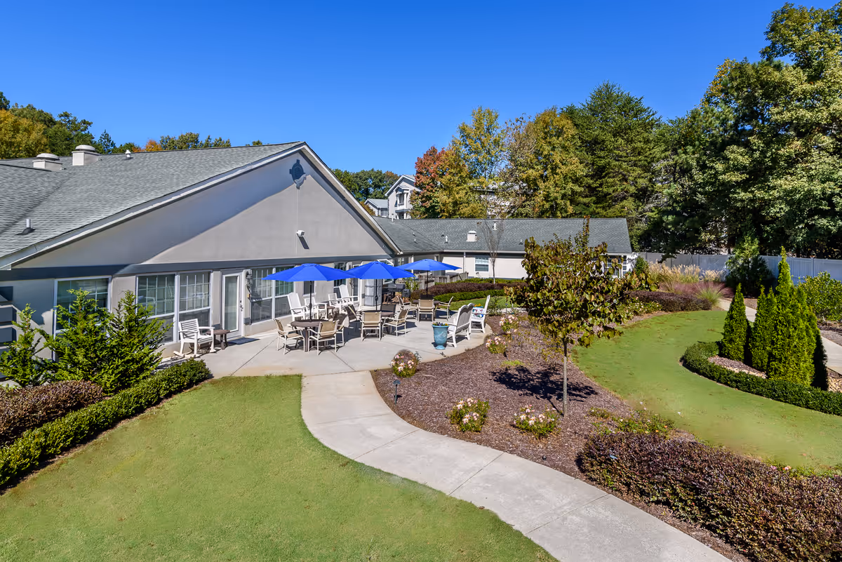 Exterior view of Maryann Adult Family Home with a landscaped courtyard and blue patio umbrellas.