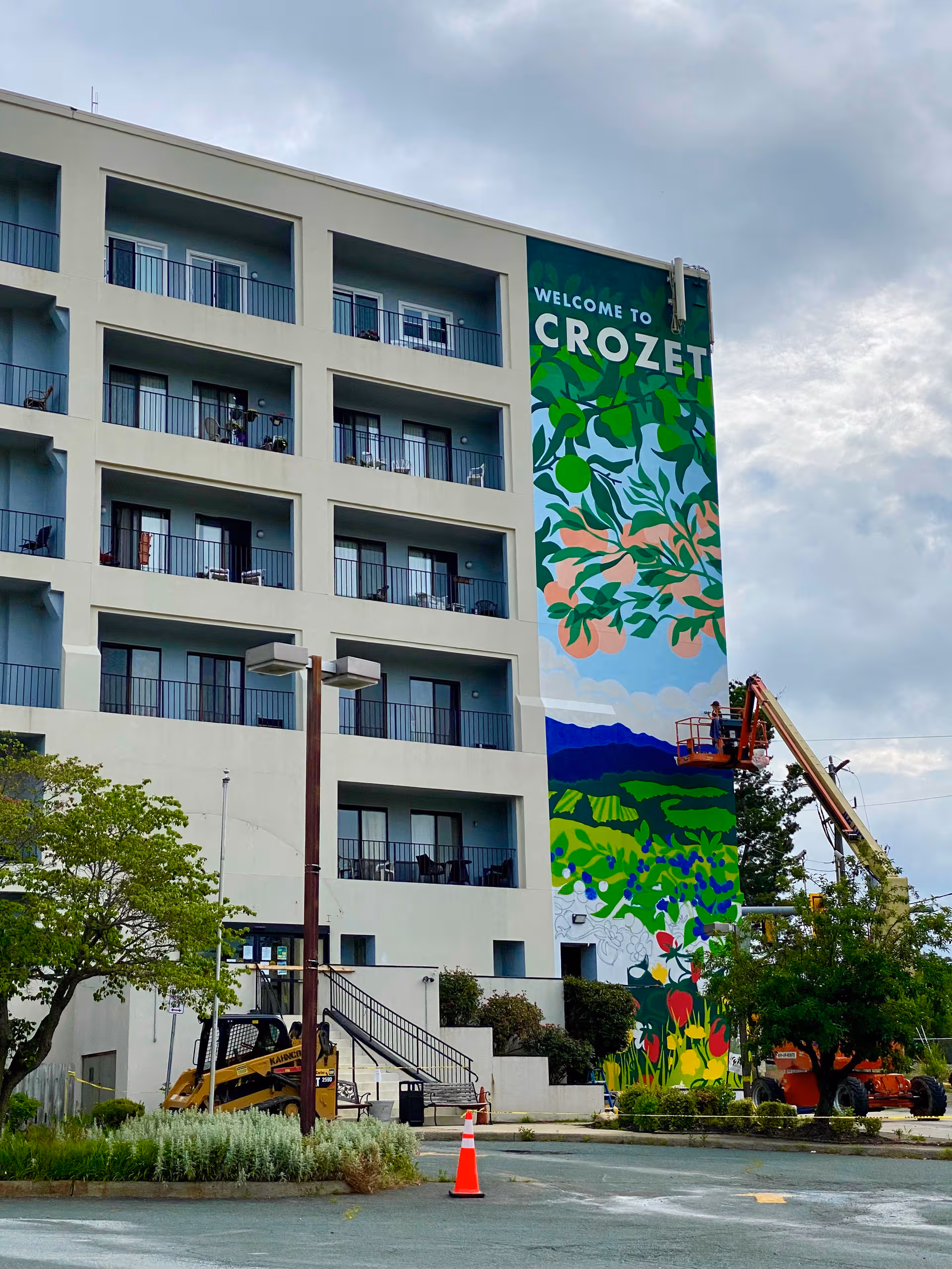 Exterior view of English Meadows Crozet Campus building with balconies and a colorful mural.