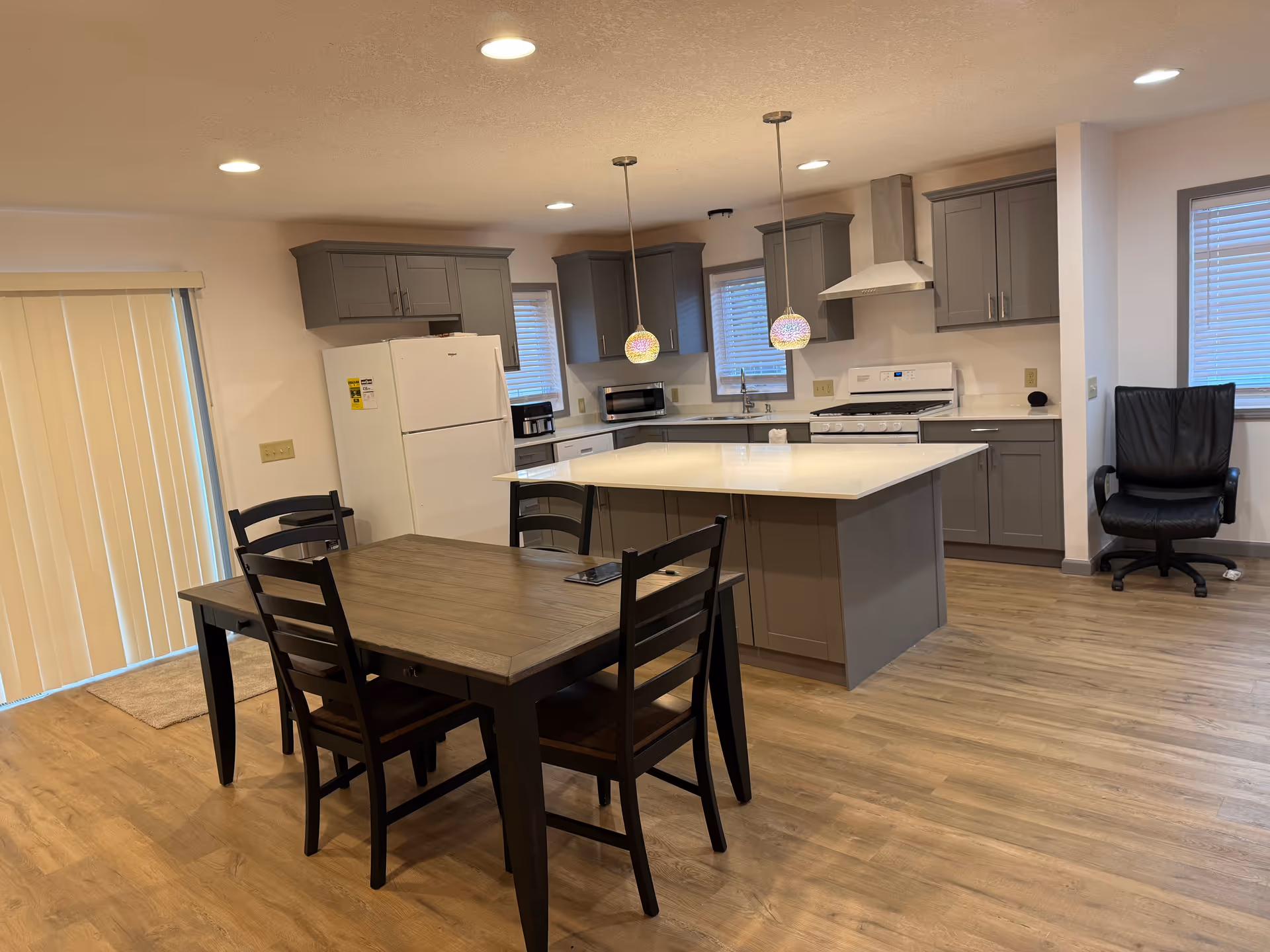 Interior view of a modern kitchen with island and dining table in a senior living facility.