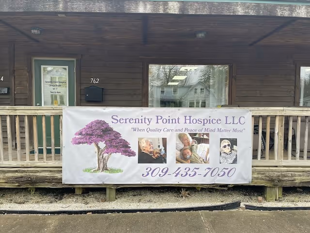 Exterior view of Serenity Point Hospice building with a banner on the porch railing.